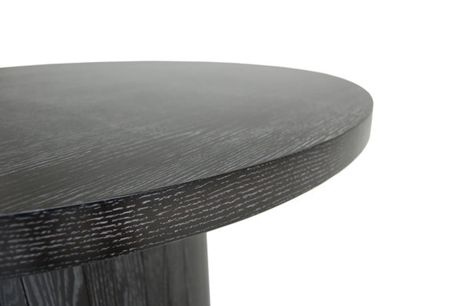 The plank wood table flaunts a cerused oak finish, which highlights the contrast between the grey surface and lightened grain, evoking a bygone era of glamour and craftsmanship.