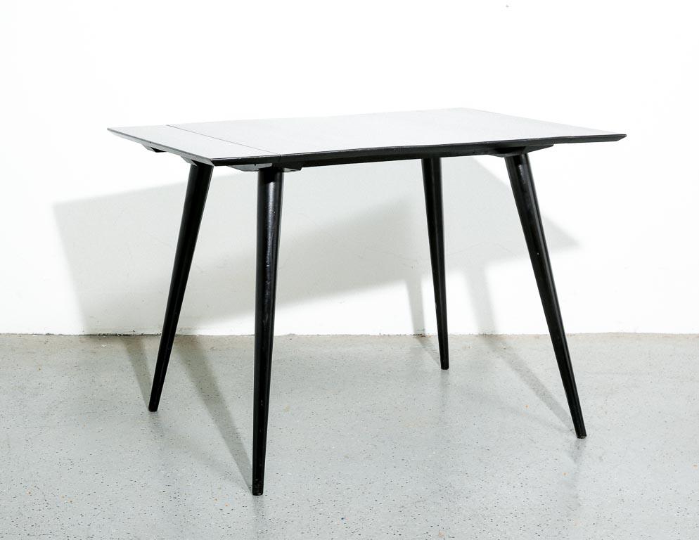 Vintage dining table designed by Paul McCobb from the 'Planner Group' collection. Black lacquered maple construction with 2 leaves. Slanted turned legs. Iconic American design.