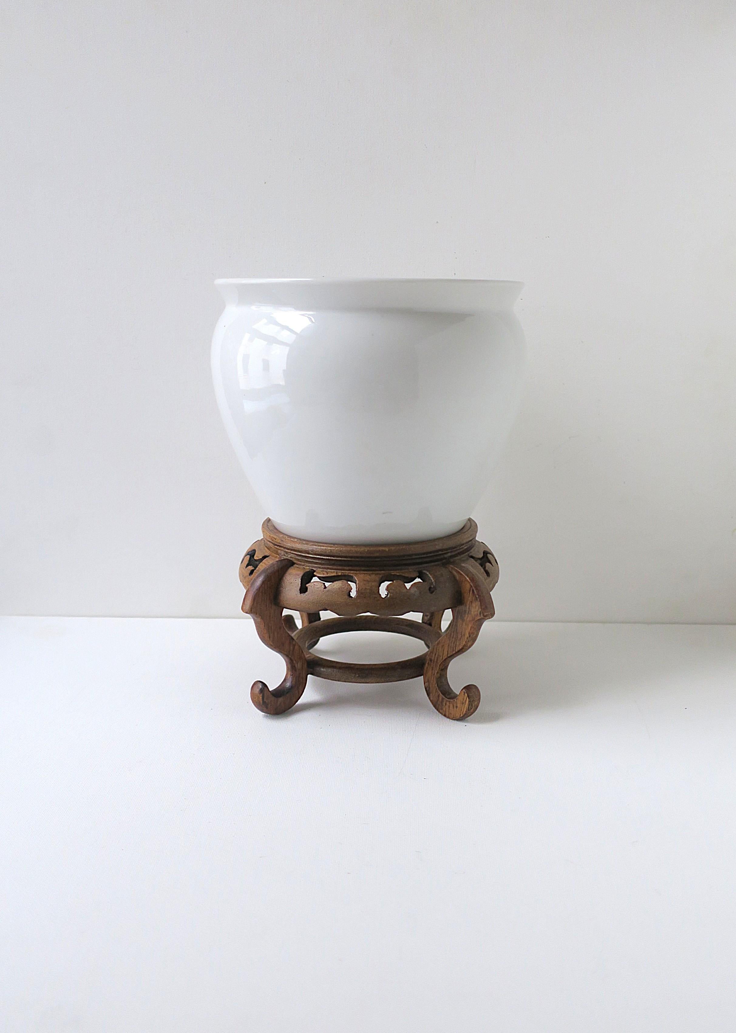 Fioriera cachepot jardinière in porcellana bianca con supporto in legno, circa metà o fine del XX secolo. Una pianta o un vaso di fiori in porcellana bianca su un bellissimo supporto in legno con ritagli e gambe a spirale. Le fioriere sono