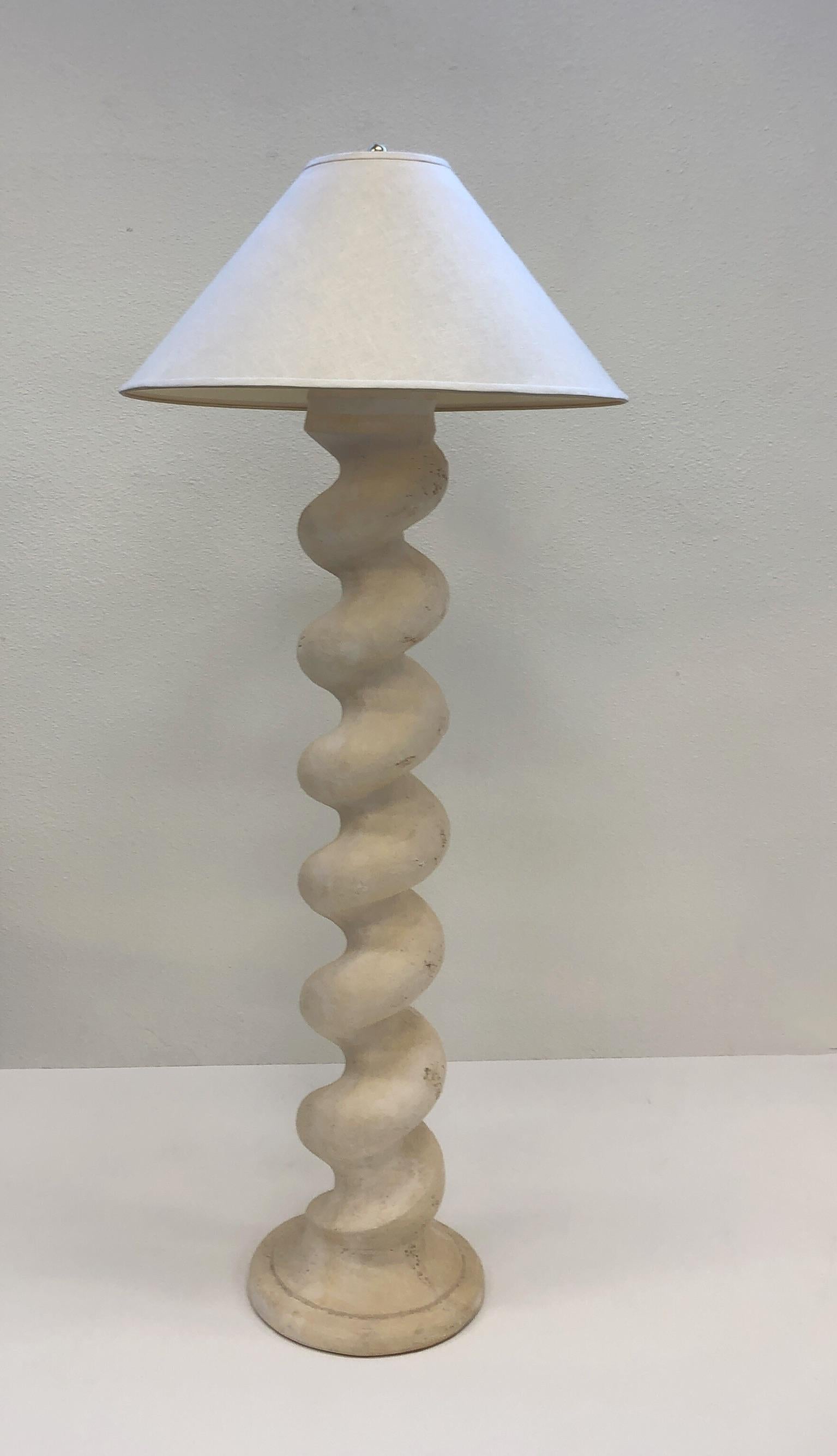 A beautiful architectural spiral column floor lamp designed by Michael Taylor in the 1970. The lamp is constructed of cast plaster and polish brass with original vanilla linen shade. 
Newly rewired. We also have the table lamp version of this in a