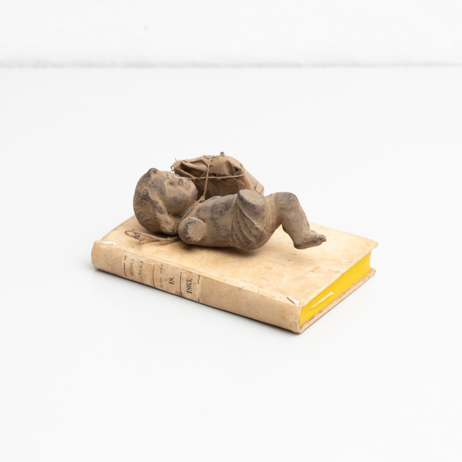 Baby Jesus plater figure and antique book artwork.    Made in traditional Catalan atelier in Olot, Spain, circa 1950.    Olot has a long tradition in the production of sculptures and religious imagery. The art and industry of religious statuary has