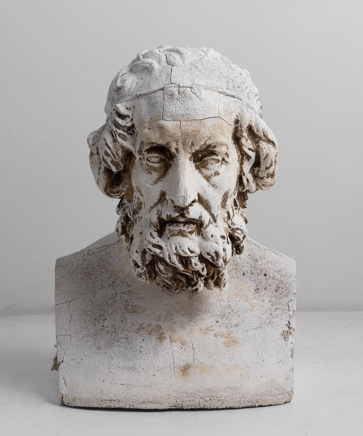 Weathered bust of a bearded man, in the Greco Roman style.