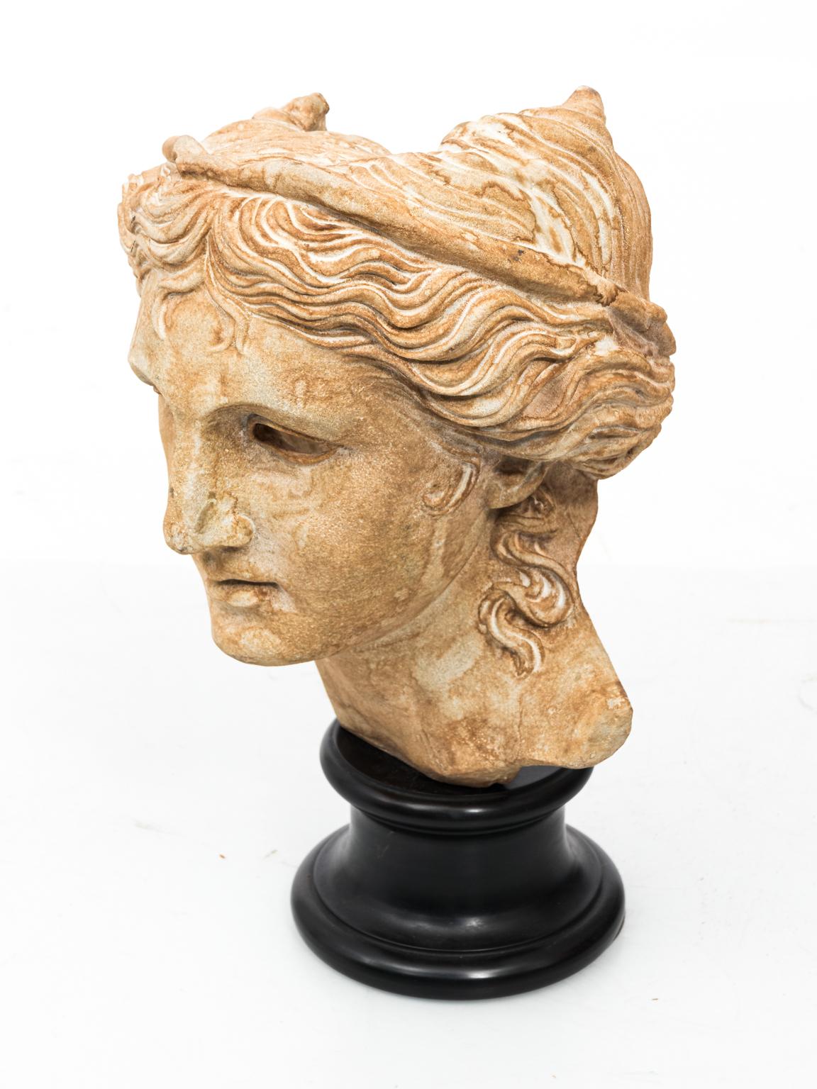 Plaster classical bust relief of a woman on a black base.