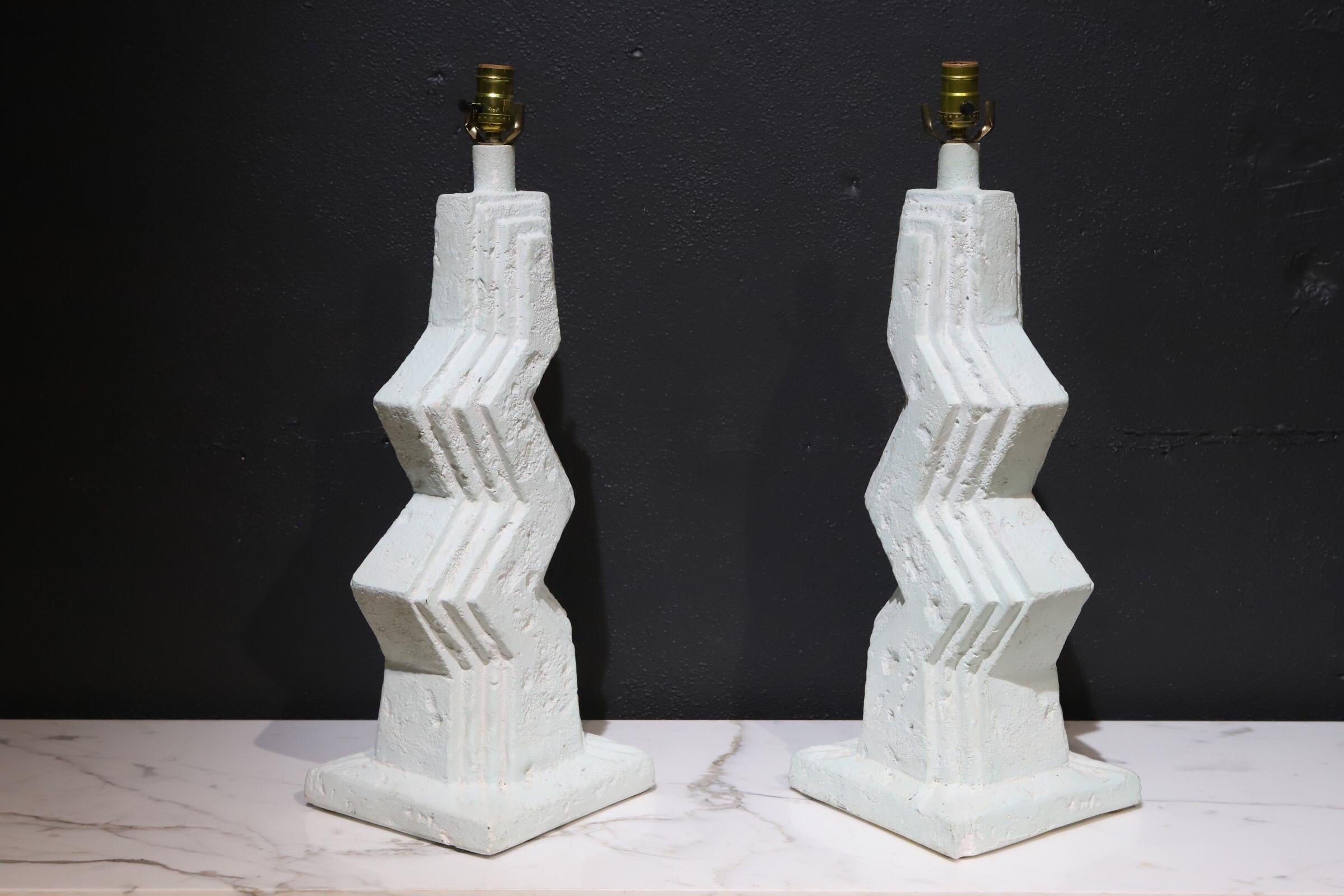 Stylish pair for artist made plaster lamps with zig zag shape. Lamps have a light greenish tint, hard to capture in photos. Pictured atop 74 inch Florence Knoll marble credenza for scale. Sold without shades.