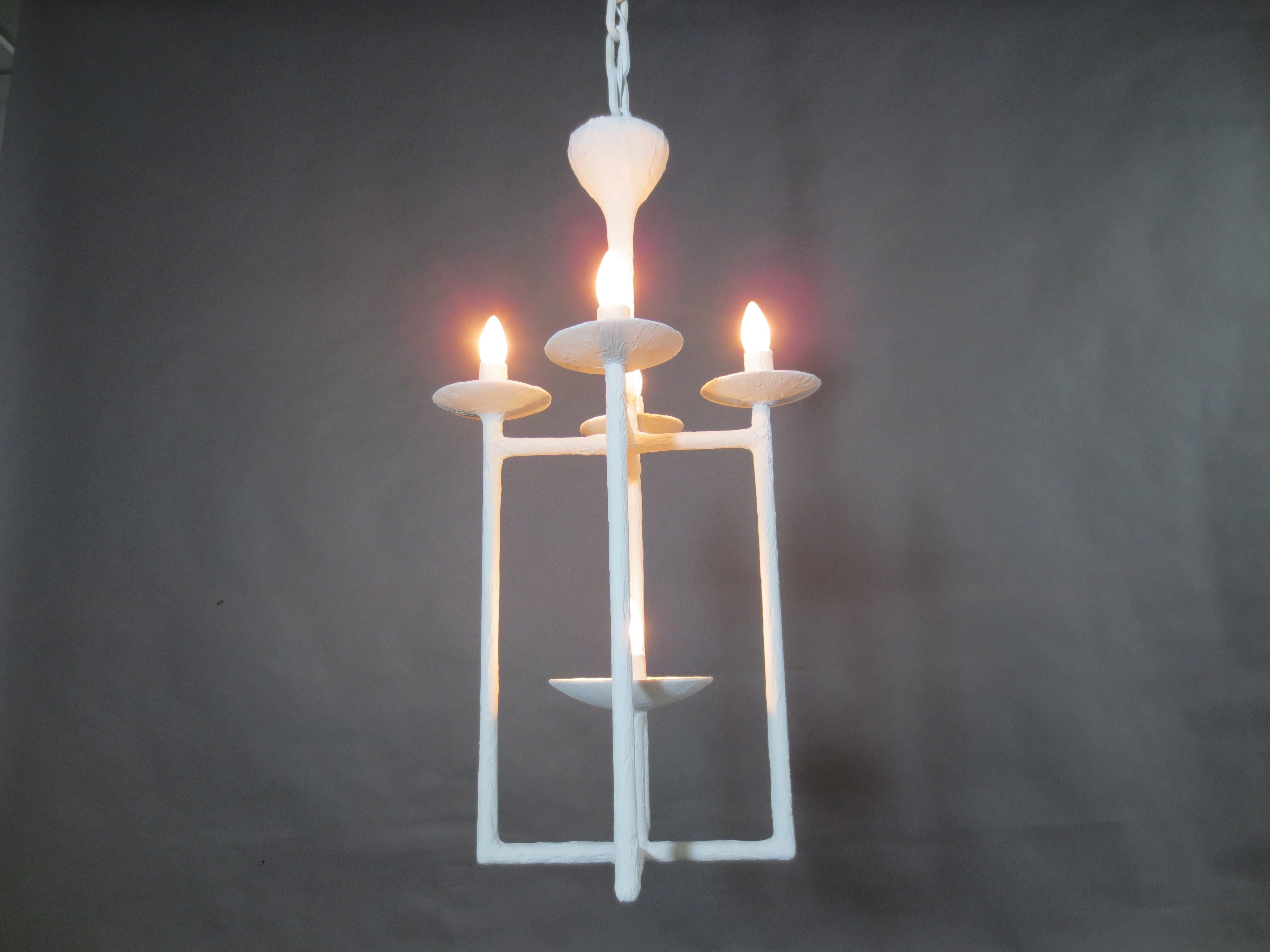 Plaster Lantern White Finish Chandelier By Tracey Garet for Apsara Interior

5 Light lantern/ pendant style chandelier. 4 Small bobeche on lantern edges and one central larger cup extending from crossbar at the base. Can be ceiling light or
