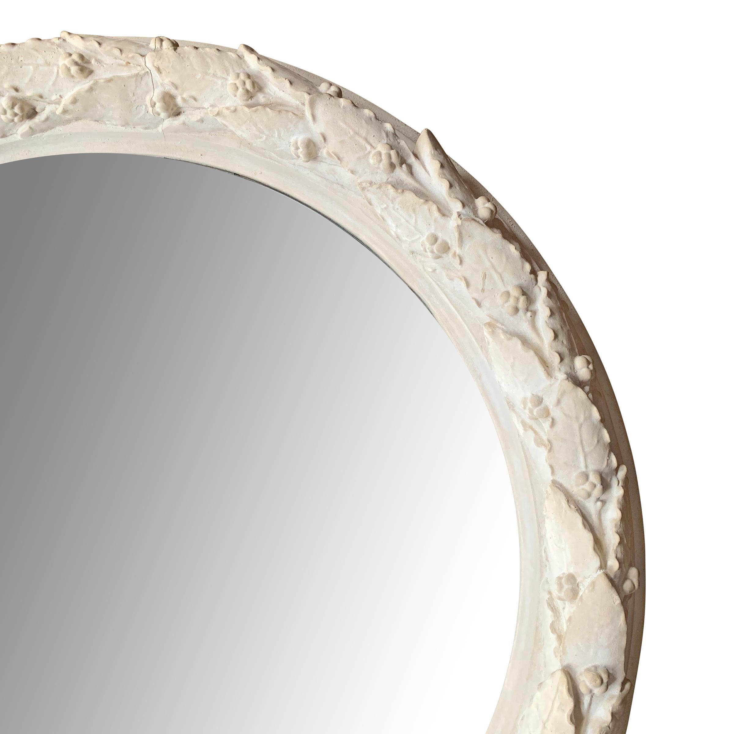 A chic mid-20th century American neoclassical style round mirror with a cast laurel wreath frame. Wonderfully sculptural!