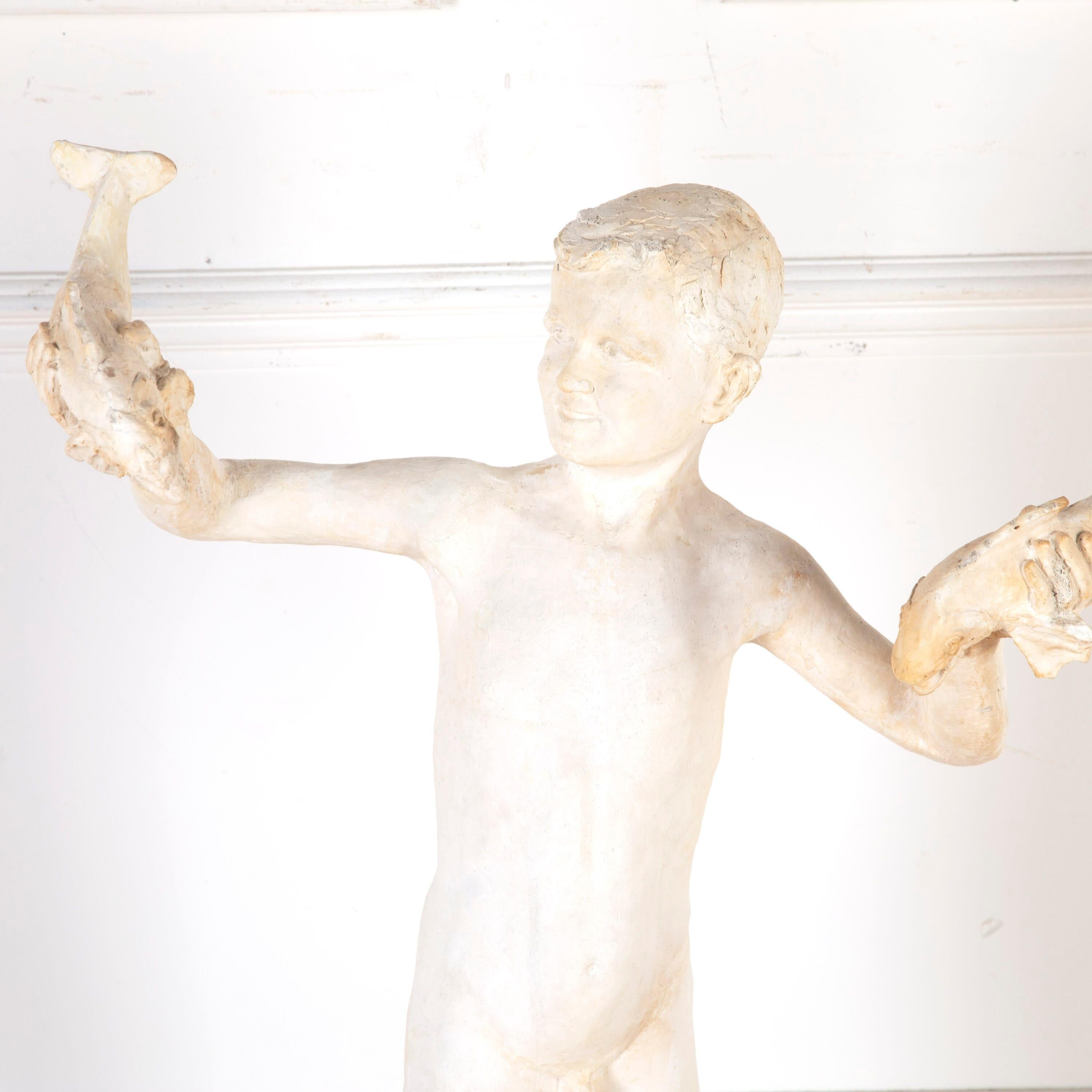 Plaster sculpture of a naked young boy holding fishes aloft. 

This charming sculpture is believed to be a maquette of John Hodges' fountain sculpture in Braintree, Essex. 

A maquette is a three-dimensional object made as a preparatory study