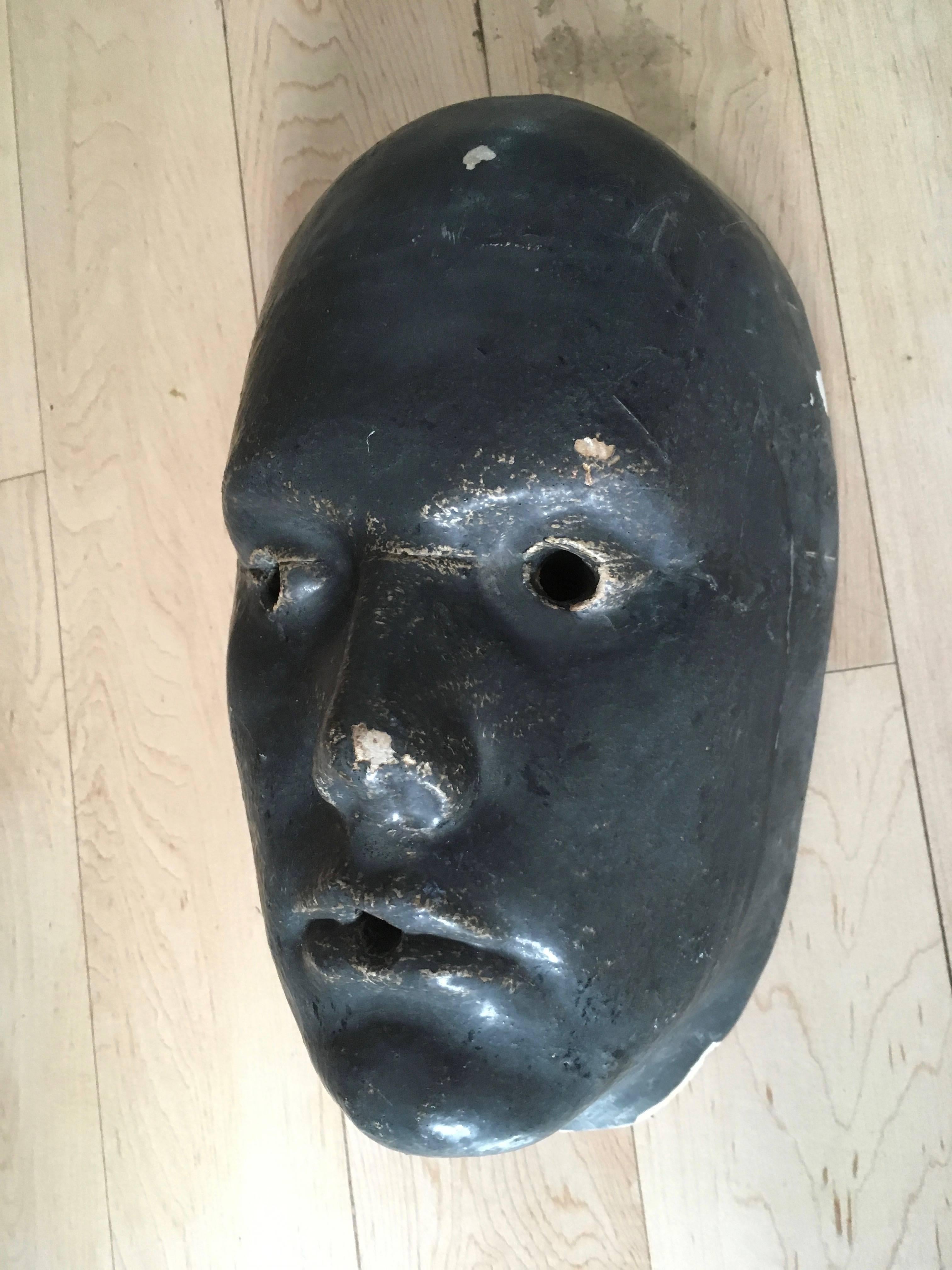 Ominous black face sculpted out of plaster. Eyes and mouth have holes. Perhaps was used as a fountain. Good vintage condition.