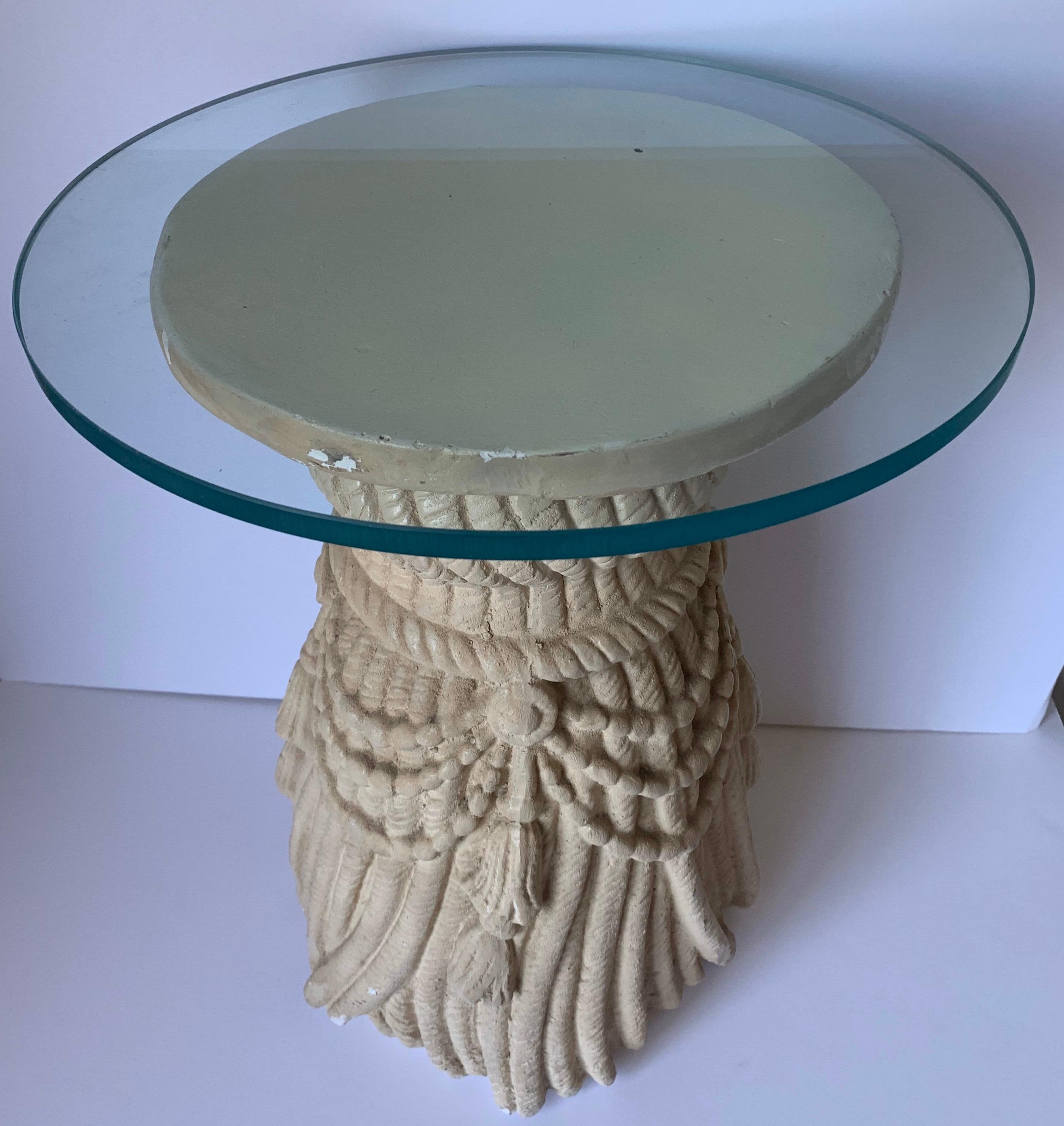 1970s tassel motif plaster side table. Original sand colored painted finish with all over age related wear. 14” round clear glass top.