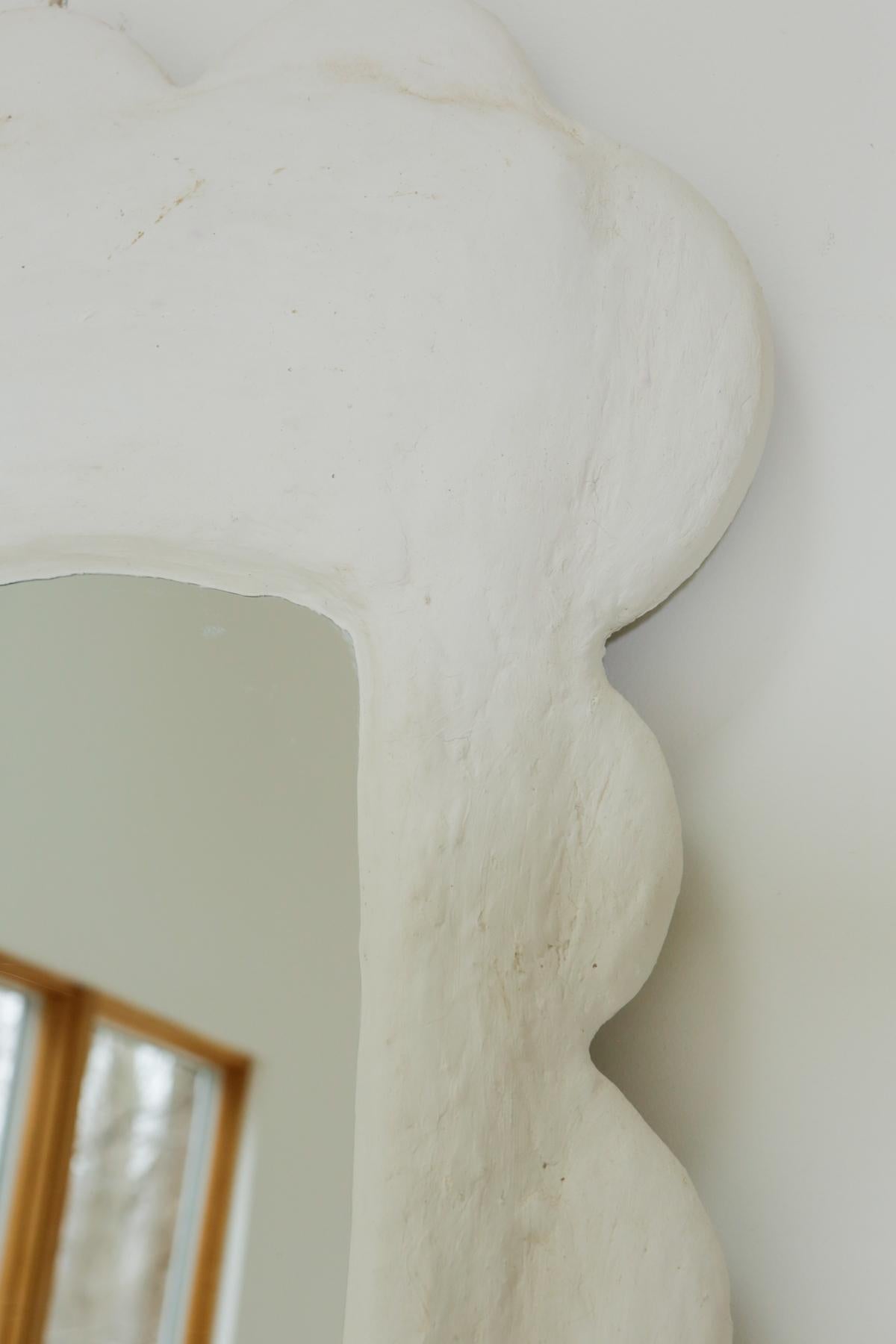 The dreamiest plaster wavy mirror that stands as if it’s a sculptural art piece. This was made using a reclaimed mirror and is built from plaster. Mirror reflects slightly narrower than true form. Due to the nature of reclaimed material and