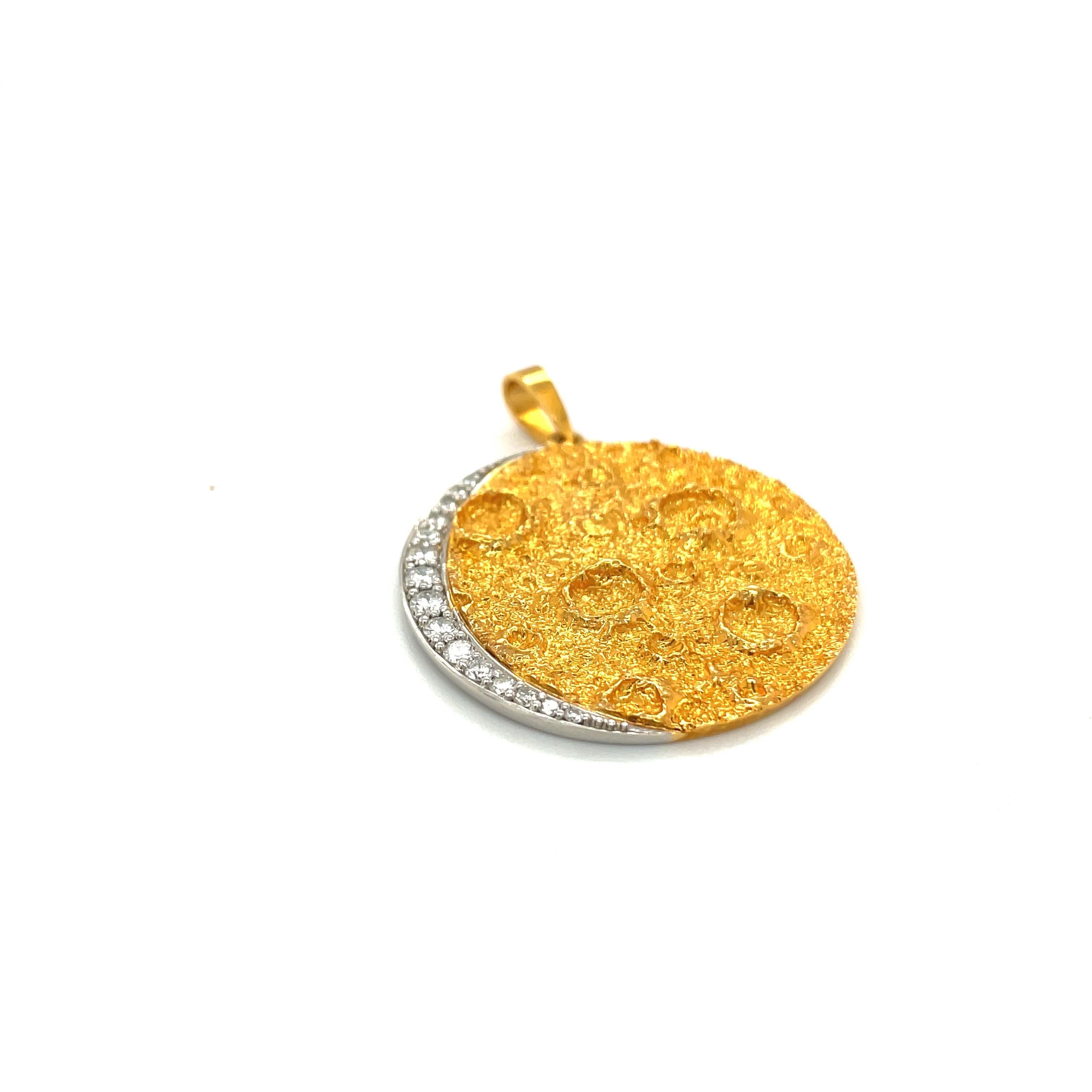 Thia 18 karat yellow gold pendant is crafted in a sand blasted finish. The pendant is designed with a texture to give the feel of the moon's craters. A platinum crescent set with 0.45 carats of round brilliant diamonds borders the pendant.
Stamped