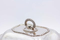 Plate covered in smooth silver with raised friezes on the edges