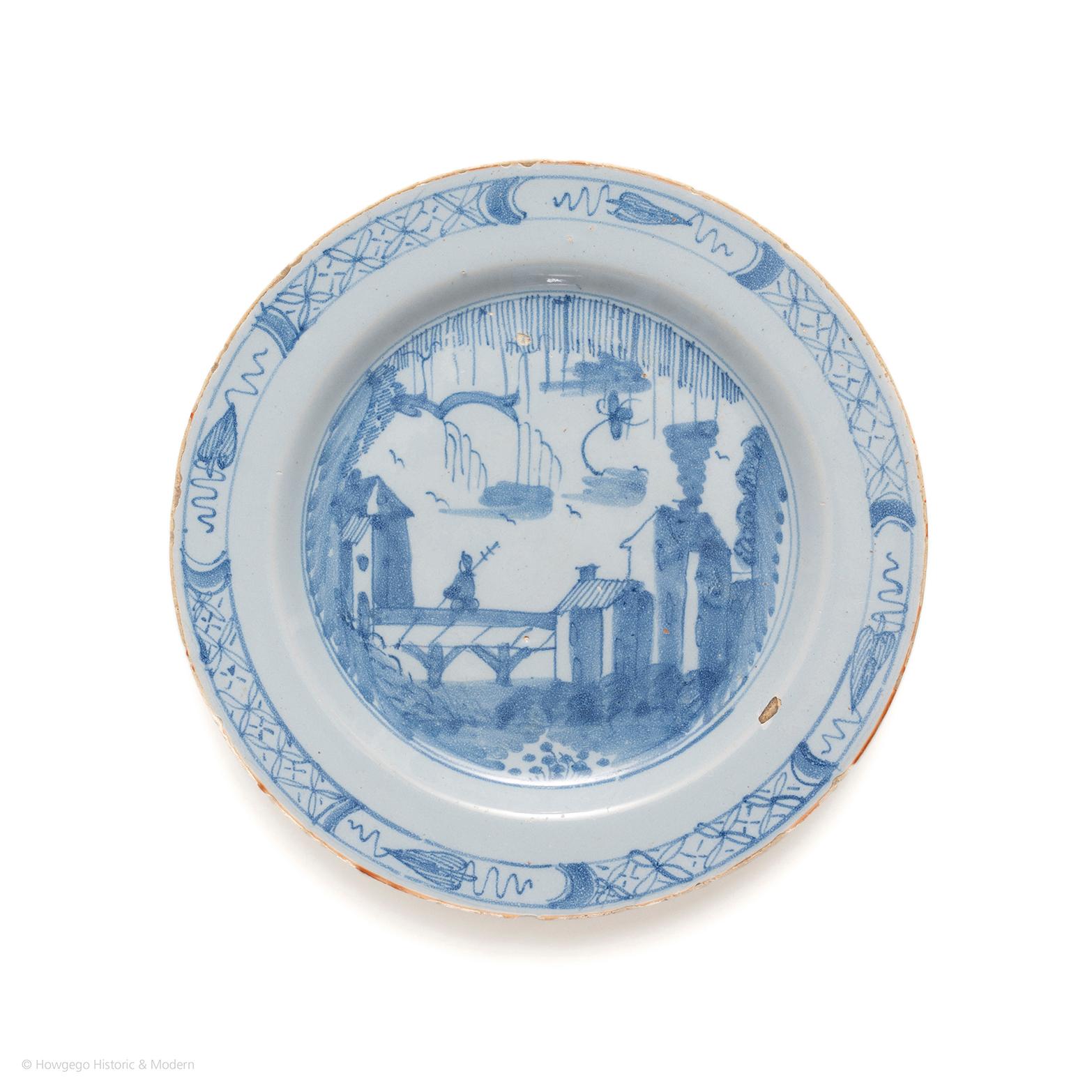 Unusual decoration blending European and Chinoiserie styles. 

Decorated with a chinoiserie scene of a soldier crossing a bridge with European houses on either side with Chinese plants and motifs. The rim decorated with a band of trellis and four