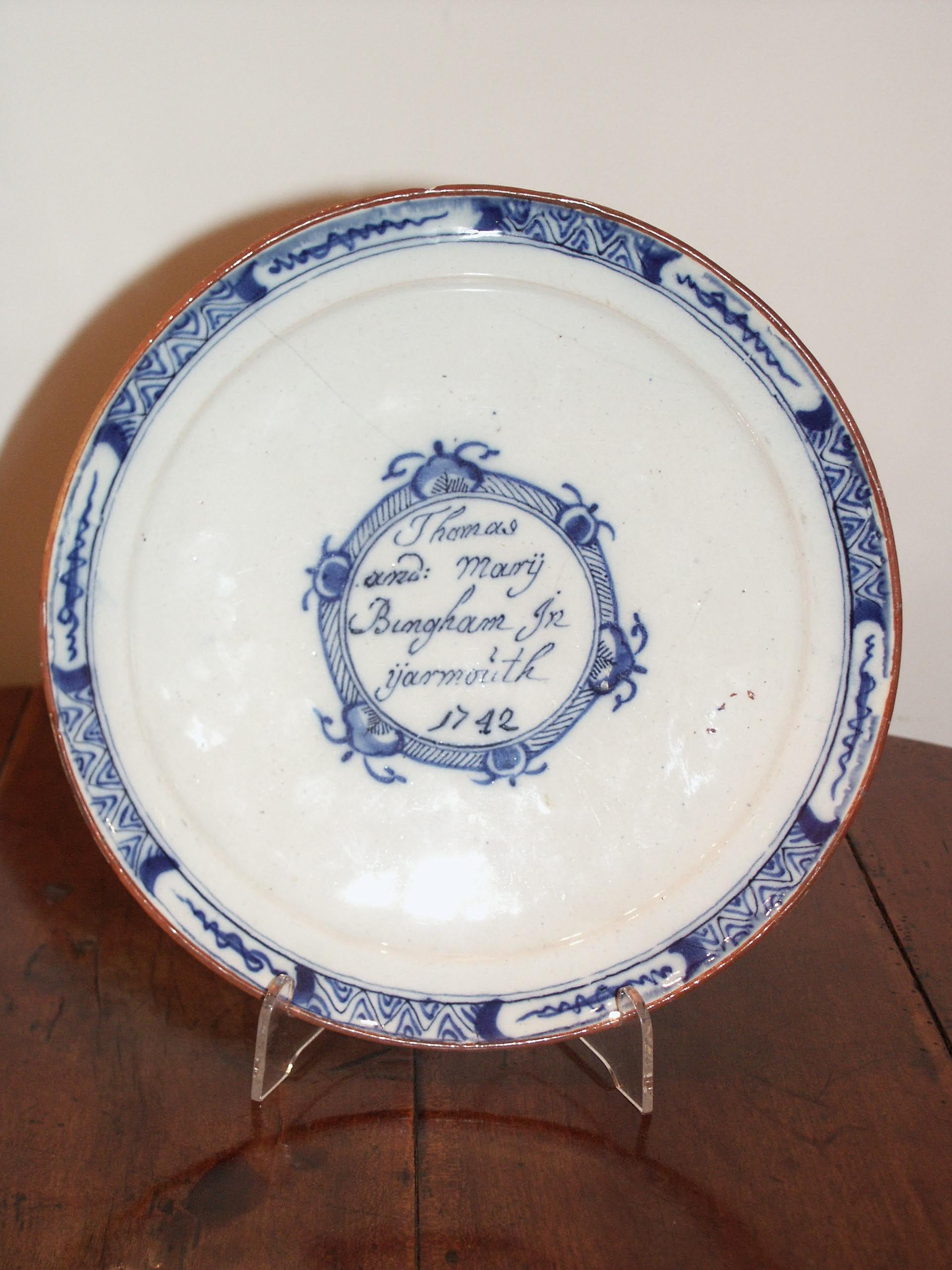 The inside centre decorated with the inscription, “Thomas and Mary Bingham In Yarmouth 1742”, inside a medallion. The rim decorated with six artemisia leaf reserves, with trellis borders interposed. The rim brown. Restoration to a rim glaze chip.