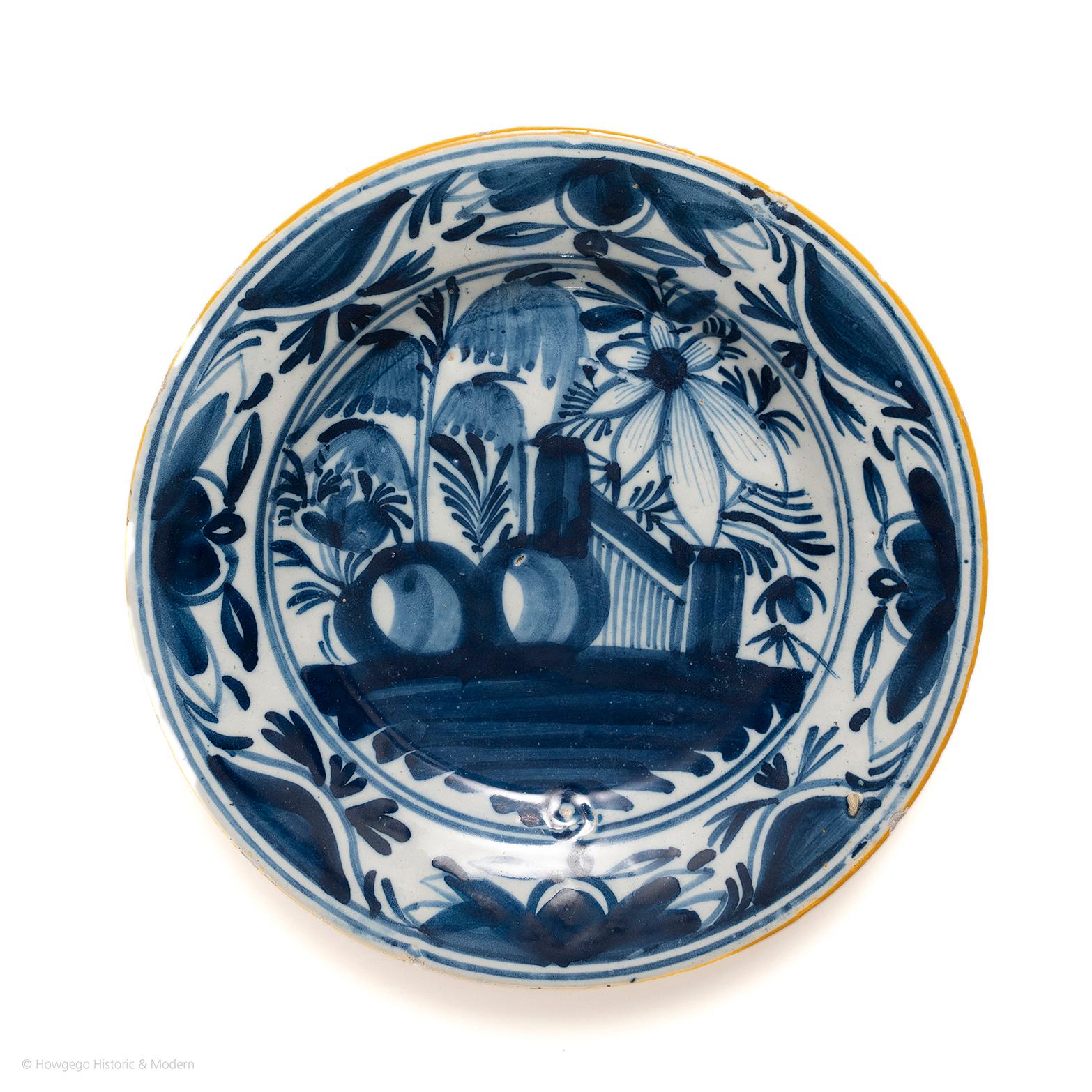Bold fluid decoration with abundant imagery associated with early Dutch pieces. 

Profusely painted with a chinoiserie garden scene with bold foliage and sprays. The rim painted with eight repeats of stylised foliage. Painted in blue on a white