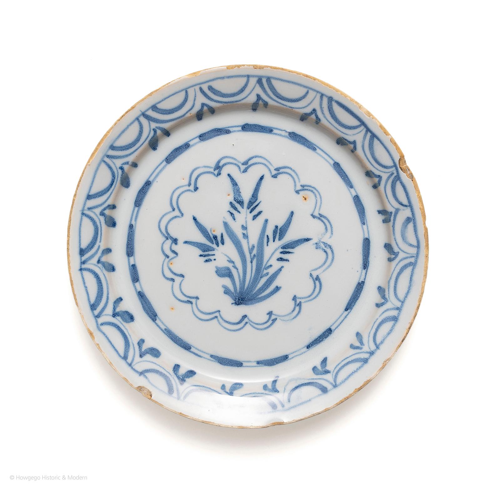 Decorated with a stylised fern surrounded by a double-circle petal shaped border and an arc border around the rim. Decorated in blue on blue glaze. In original condition. Probably London, circa 1720.
diameter 19.5cm., 7 3/4