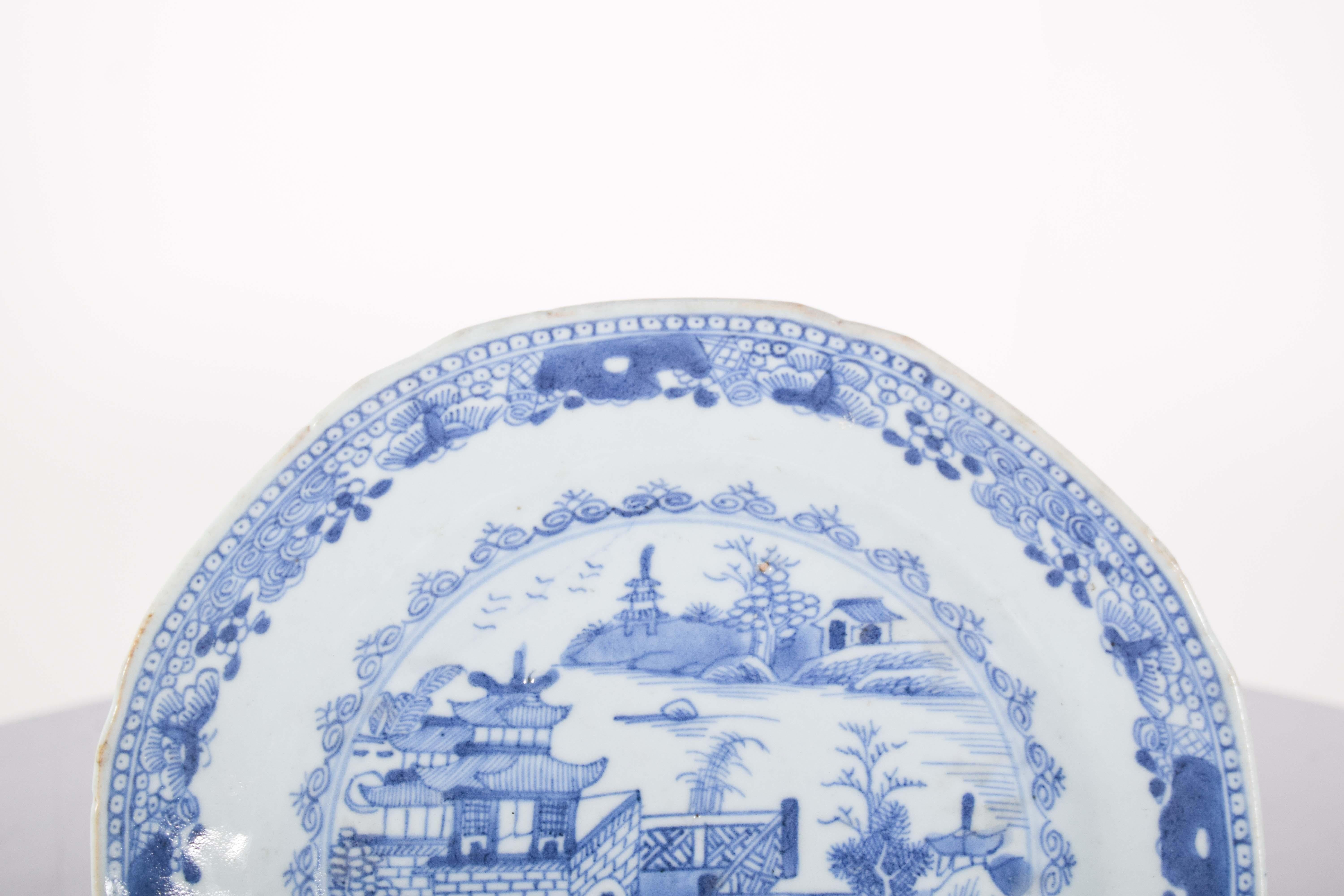 Chinesischer Porzellanteller für den Export. Blaue und weiße Verzierung, die in der Mitte eine Flusslandschaft mit Brücke, Haus und Pagode darstellt. Qing-Dynastie, Qianlong-Periode (1736-1795).
In der Mitte der Platte ist eine Flusslandschaft zu