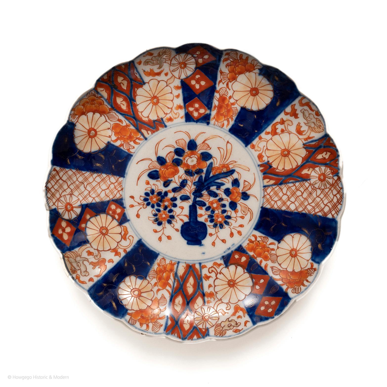 Ein charmanter, gelappter Imari-Teller aus dem 18. Jahrhundert mit Drachenornamenten. Wunderschön bemalt mit einer Vase und einer Fülle von Blumen, umgeben von einem doppelten Kreisrand. Die äußere Bordüre mit kunstvollen Vignetten mit