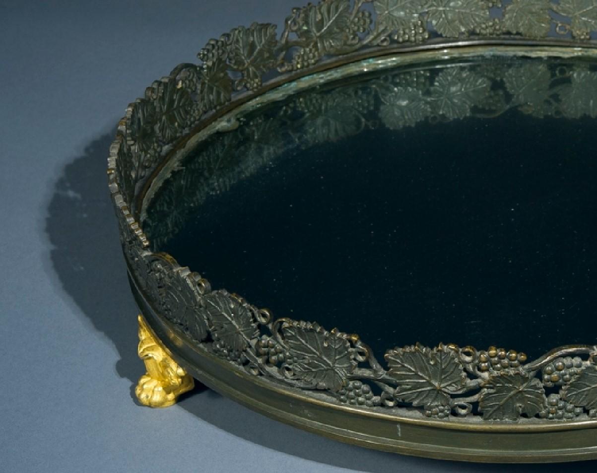 French.
Plateau in the Restauration taste with grape and leaf motifs, circa 1825.
Ormolu and patinated bronze, with mirror plate and wood backing.
Measures: 15 7/8 in. diameter, 3 11/16 in. high.

Condition: Excellent.