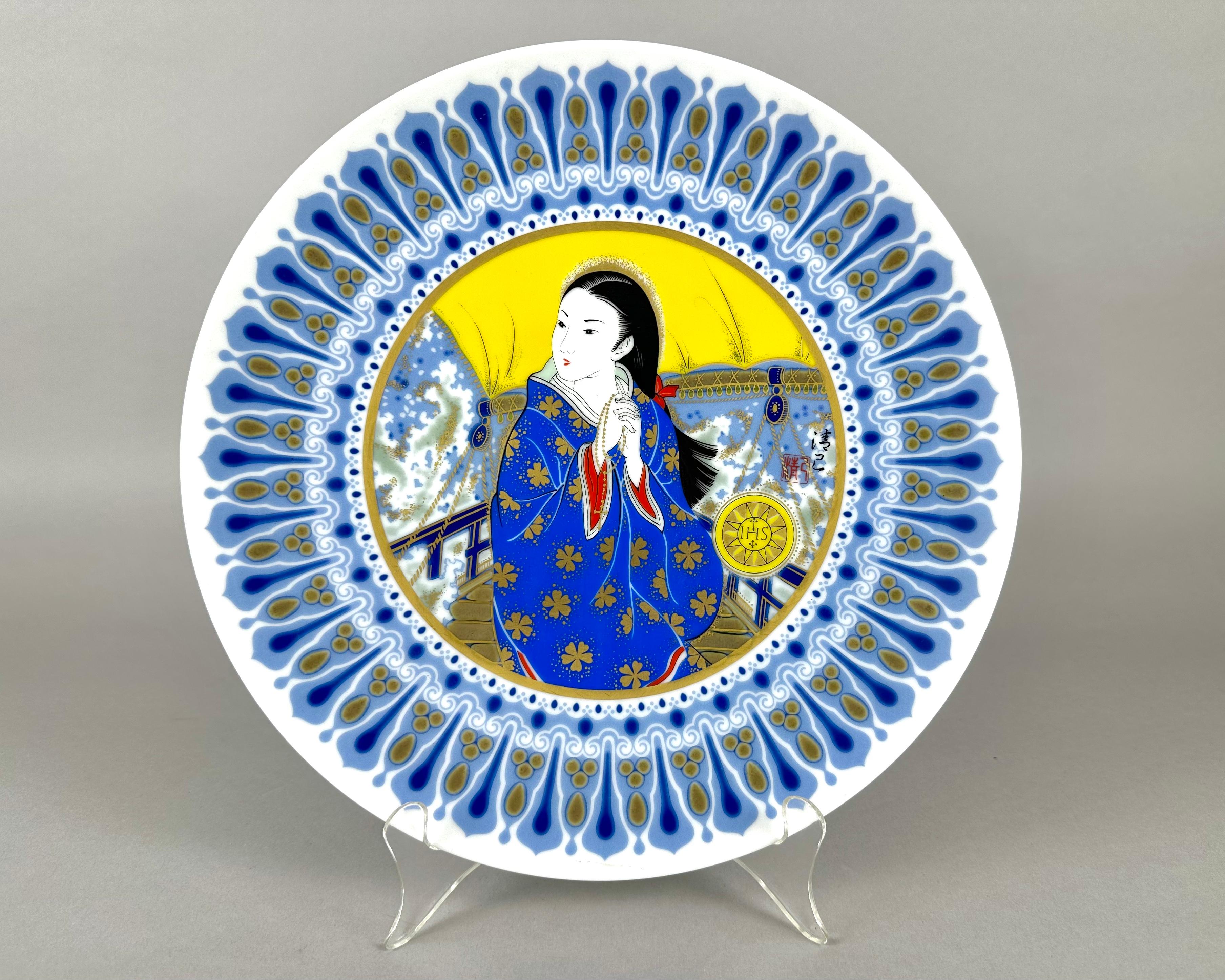 Discontinued Noritake plates have multicolor image with Asian woman and man in center, with gold tone band and highlights.

Designed by: Kiyomi Akagi.

The Japanese porcelain manufacturing company Noritake is considered one of the best in the