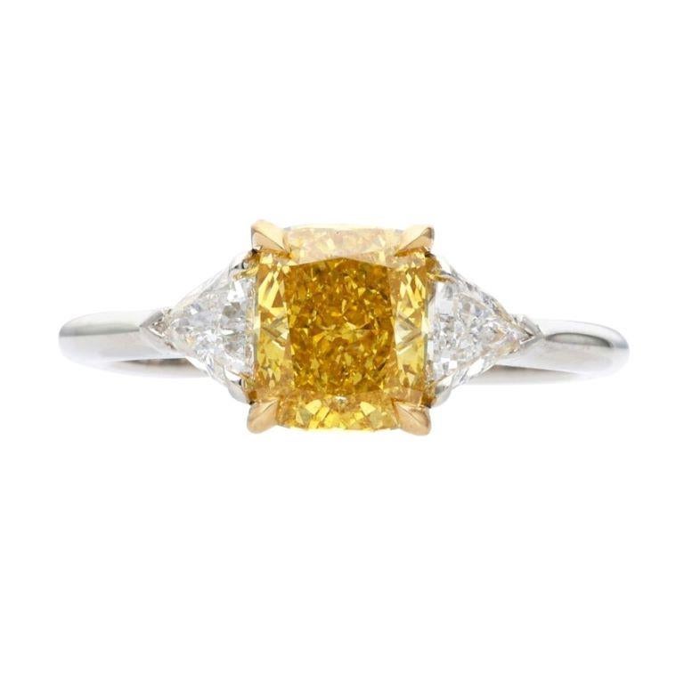 Centering a Fancy Intense Orangy Yellow diamond, flanked by 2 trilliant cut diamonds.
 - Fancy Intense Orangy Yellow diamond weighs 1.36 carats
 - Trilliant cut diamonds weighing a total of approximately 0.60 carat
 - Platinum and 18 karat yellow