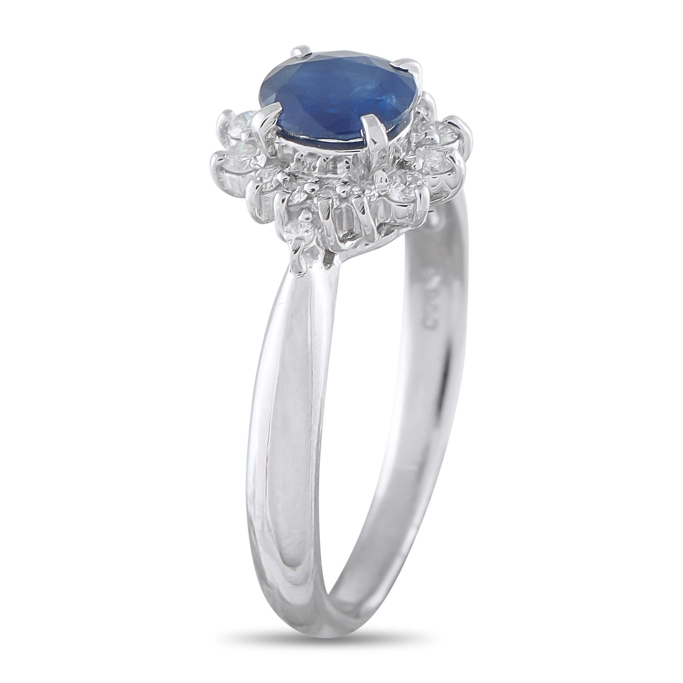 Raised high by four delicate claw prongs is a vibrant 0.72-carat oval sapphire, supported by a slim platinum band. The deep blue stone is dramatically framed by a starburst halo of petite round diamonds, maximizing its visual impact. This piece is