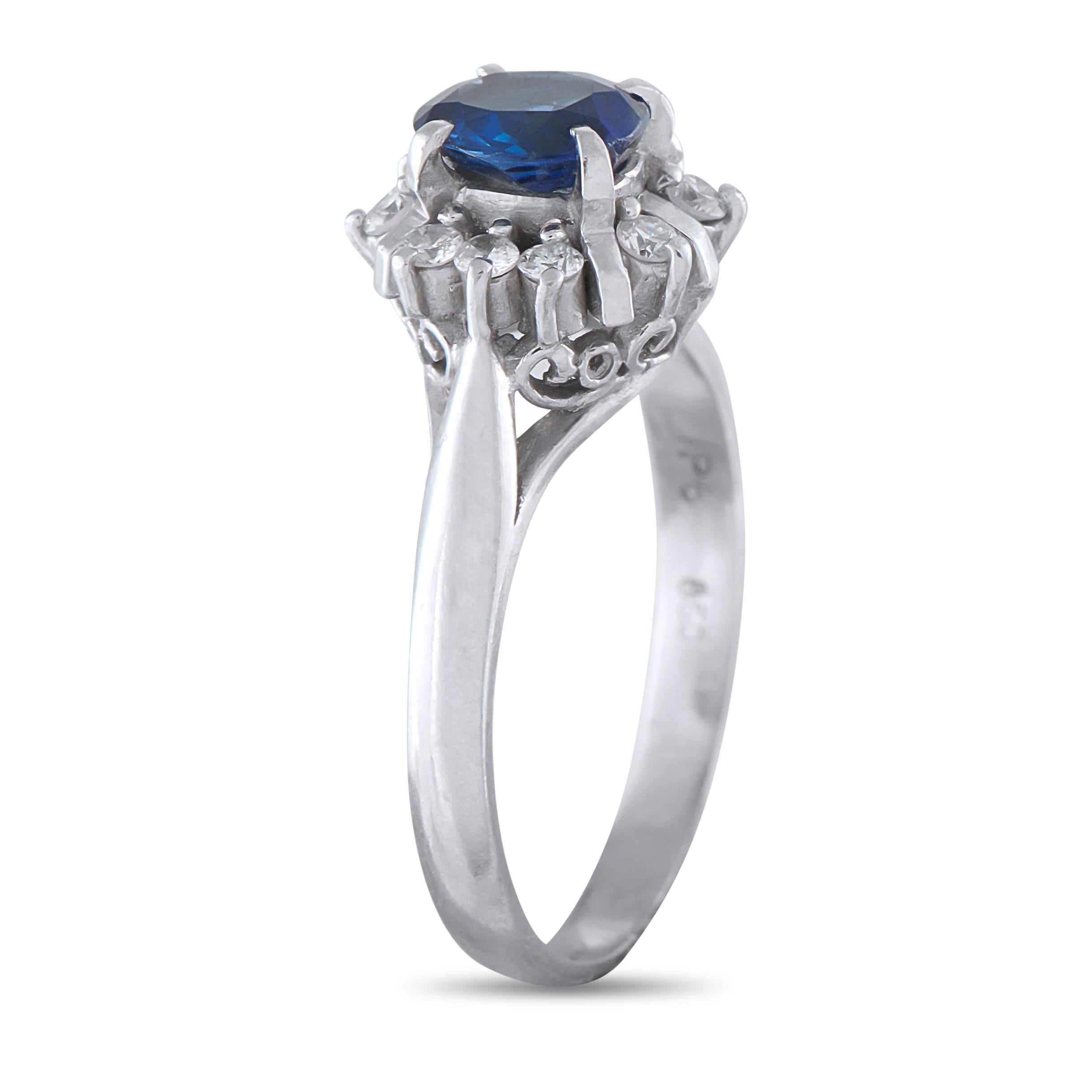 A 0.82-carat oval sapphire rises on four prongs above a cathedral shank, commanding attention with its deep blue hue. Round diamonds, each held by two prongs, encircle the sapphire center stone. The prongs themselves add dimension and architectural