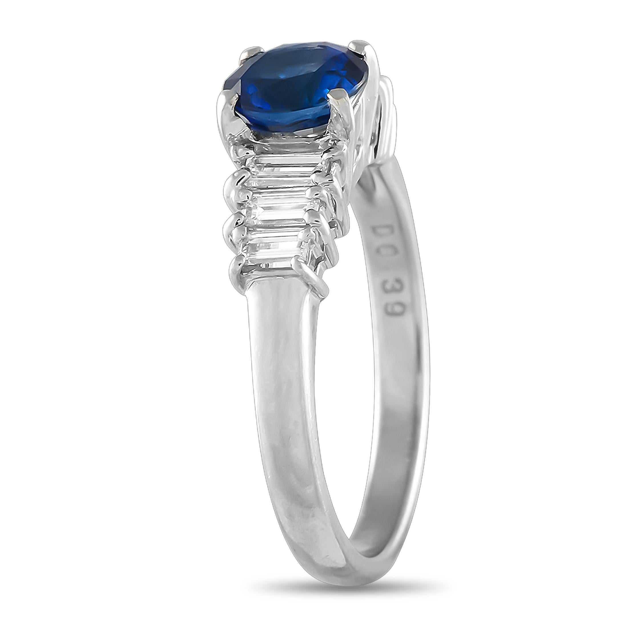 A platinum ring that merges the brilliance of diamonds with the allure of a sapphire. This elegant ring with a royal appeal features a polished band topped with a round sapphire on four prongs. On either side of the blue gem are trios of baguette