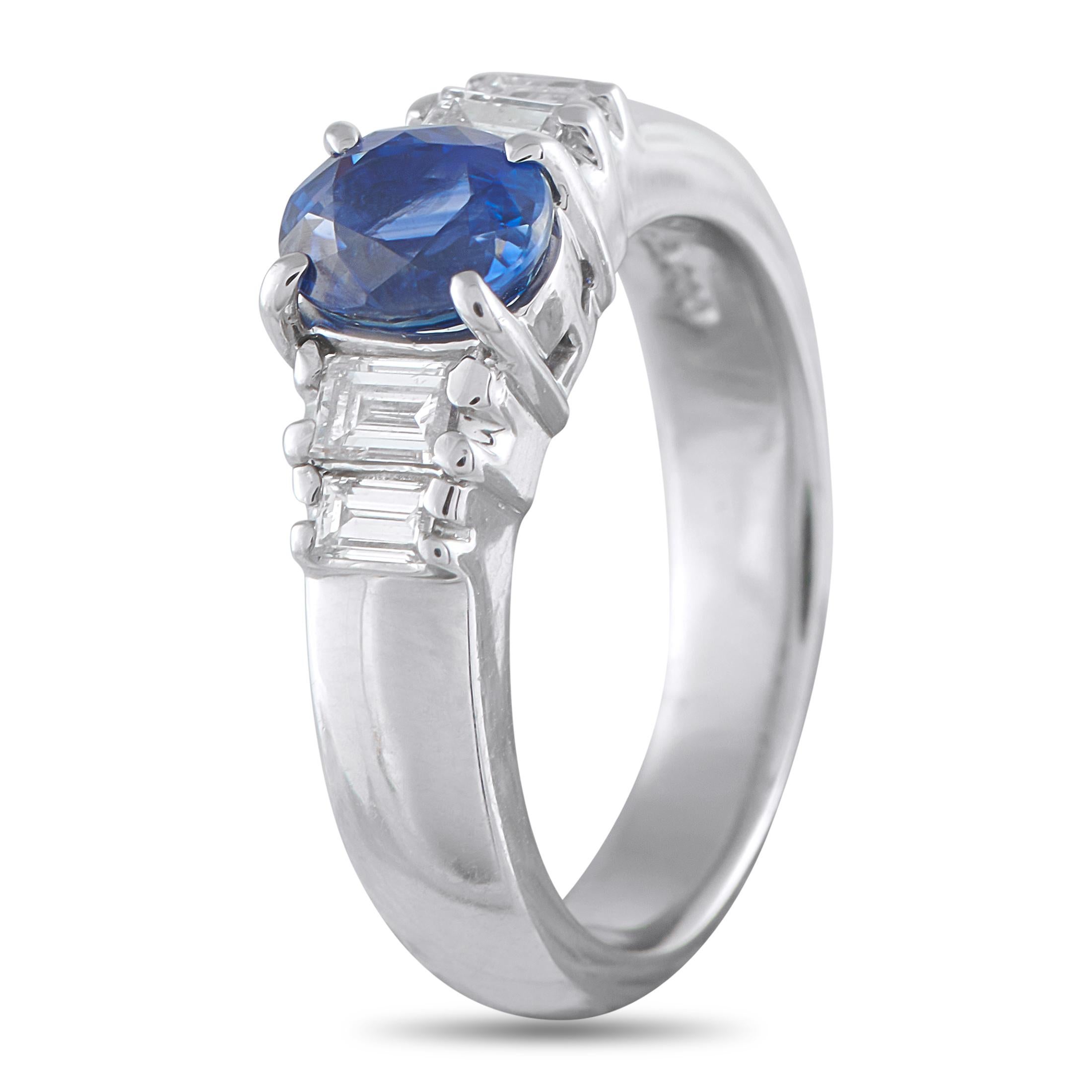 A 1.32-carat oval sapphire serves as the focal point, held securely by four prongs that balance protection with visibility. Flanking the blue gem, two baguette diamonds on each side taper gently toward the band, creating a tiered effect that