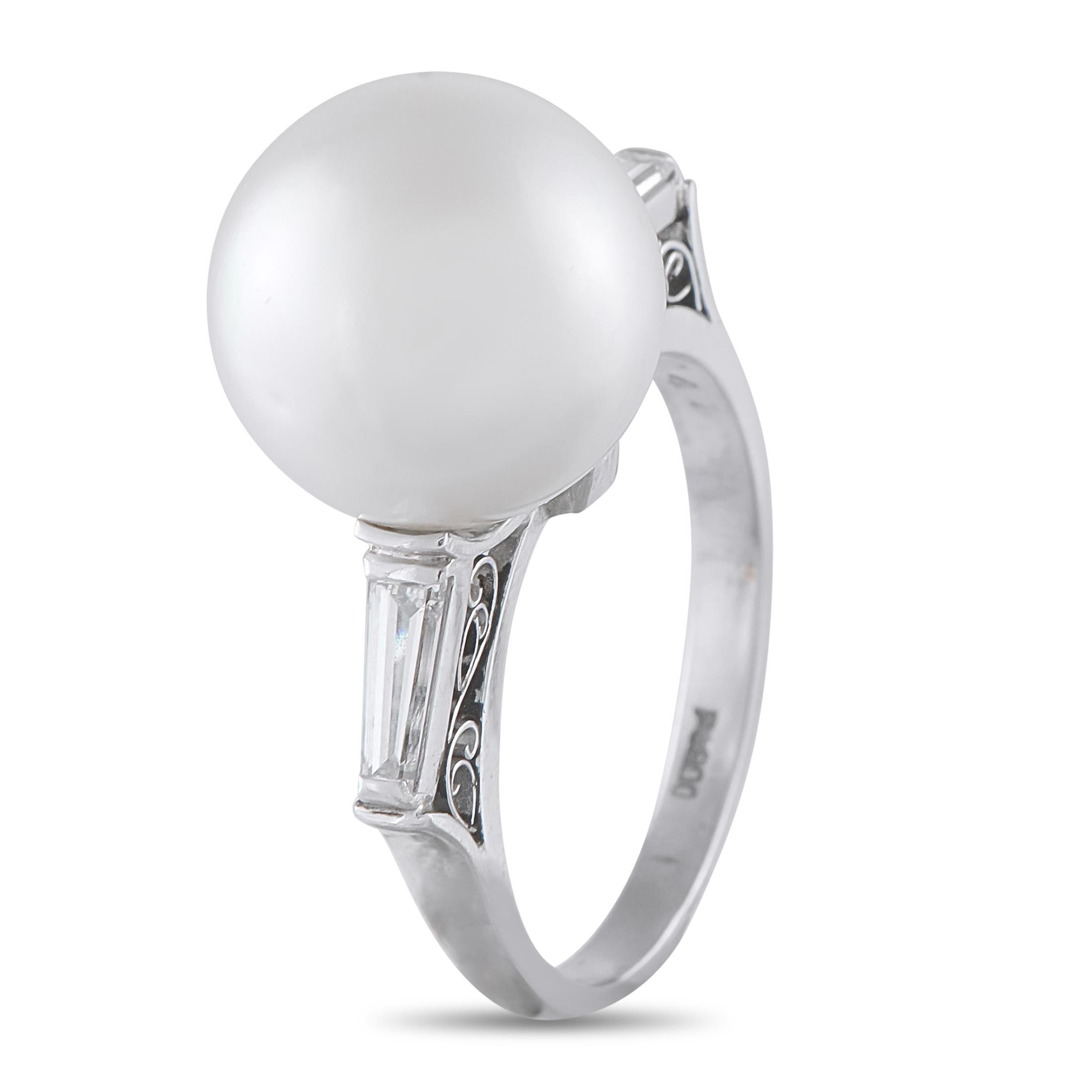 Luminous and impossible to overlook. Rising 17mm above the finger, this ring lets its 12.5mm pearl take center stage. Tapered baguette diamond side stones flank the gem with precise brilliance, while a filigree gallery beneath lends charm to its