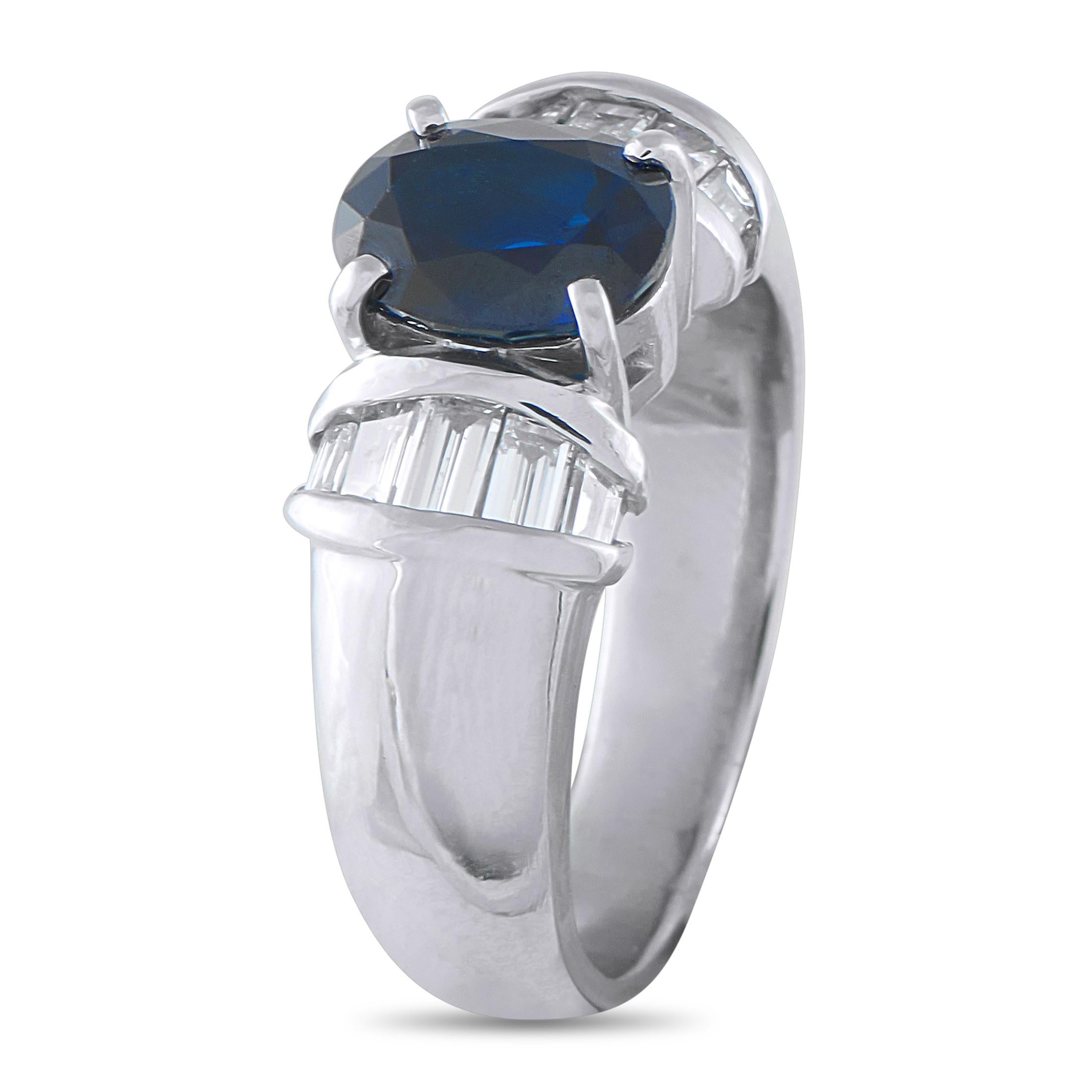 A spectacular 2.18-carat oval sapphire takes center stage, held securely by four classic prongs. Flanking the rich blue center stone are neat collars of baguette diamonds, set within a contemporary channel setting that provides crisp, linear
