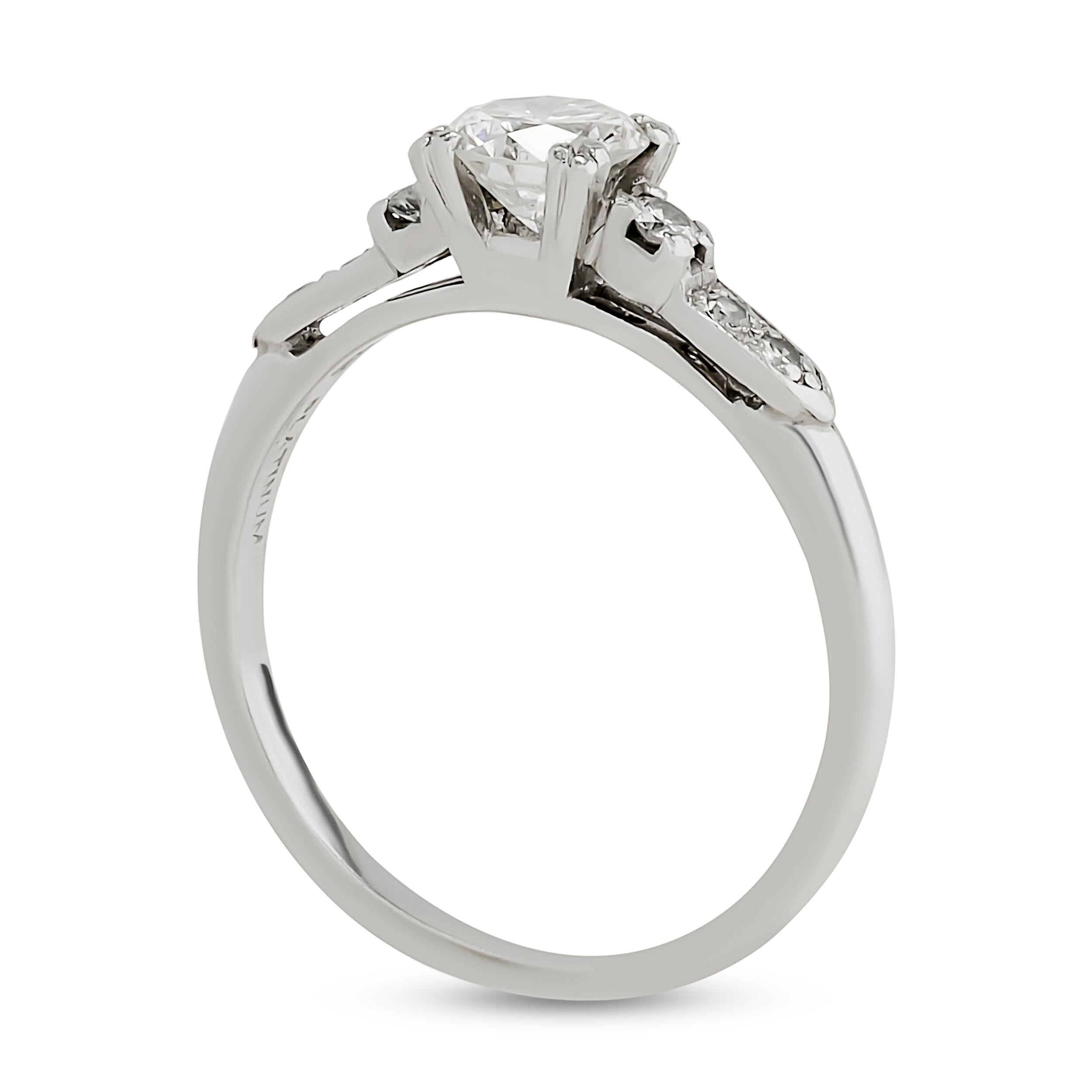 This platinum diamond ring features a round brilliant center stone held by four prongs, flanked by smaller accent diamonds prong set in a channel along the shoulders, creating a classic and elegant design.

Center Round Diamond - Approximately 0.50