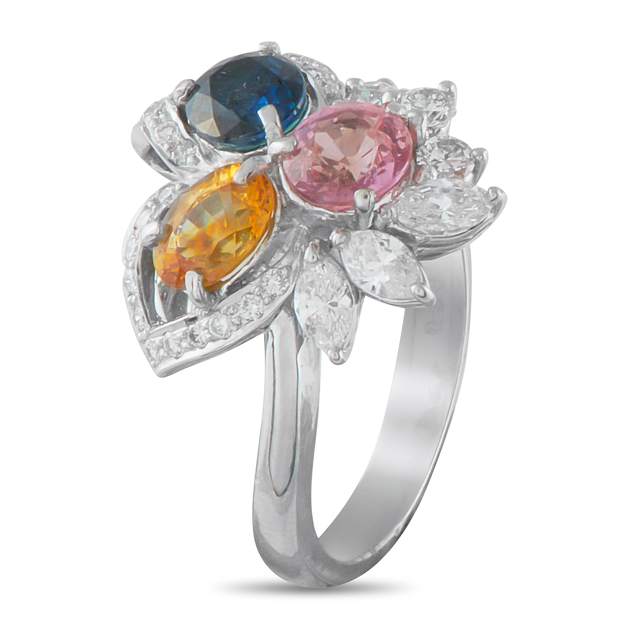 This ring's exceptionally feminine design features a trio of sapphires in vibrant blue, sunny yellow, and delicate pink. The chromatic centerpiece is surrounded by leaf-inspired curved rows of brilliant round diamonds, complemented by marquise and