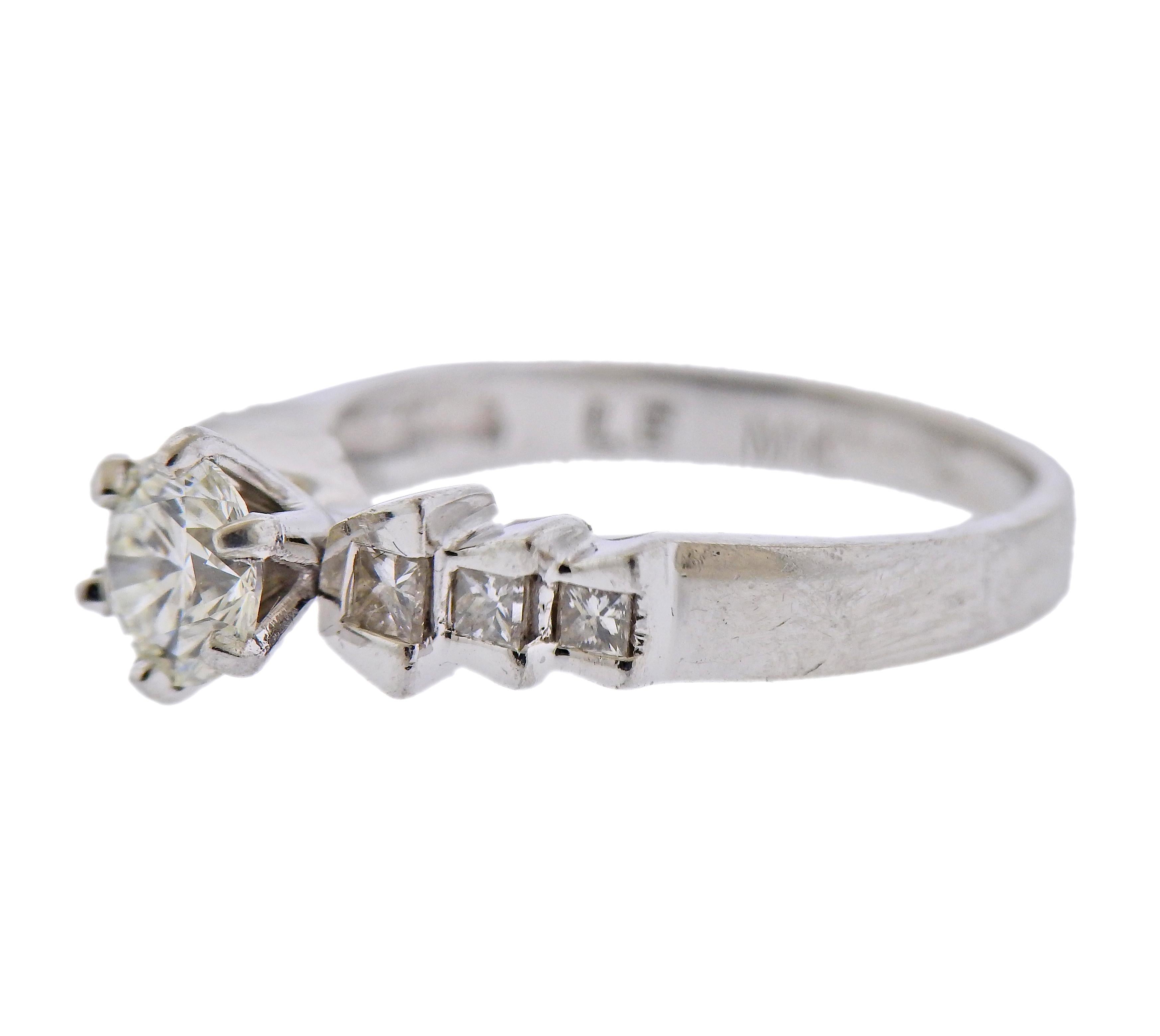 Platinum engagement ring with center approx. 0.75ct H-I/VS1-VS2 round brilliant stone, and approx. 0.26cts in princess cut stones on sides. Ring size 7.25. Marked: Plat, LE MK. Weight - 6.4 grams. 