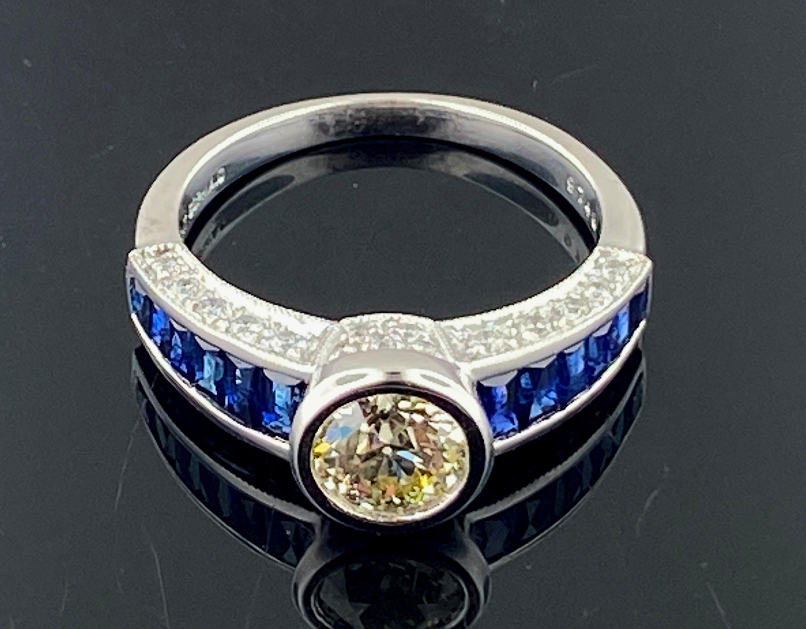 Set in Platinum, weighing 6.63 grams, is an 0.75 carat Old European Cut center diamond, Color: N-O, Clarity: VS-1, accented on the sides with 12 French Cut Blue Sapphires weighing 1.15 carats and 31 Round Brilliant Cut diamonds weighing 0.30 carats.