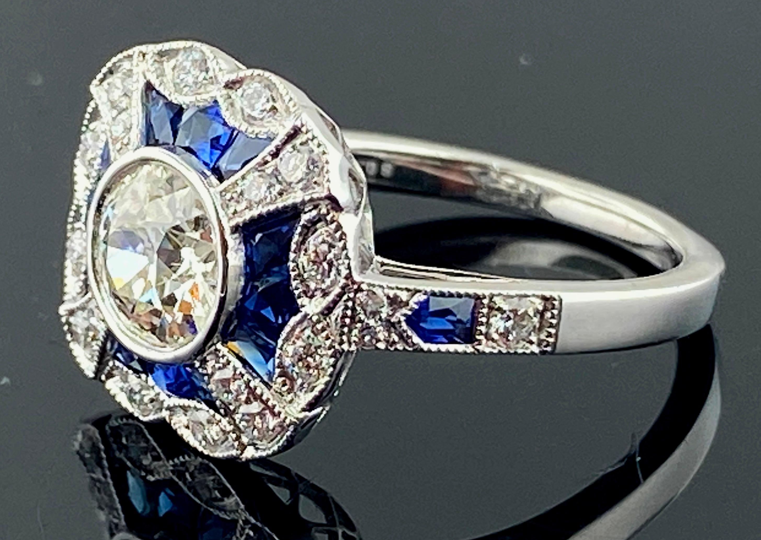 Set in Platinum, weighing 4.53 grams, is an 0.75 carat Old European Cut center Diamond, Color: H-I, Clarity: VS-2,  Surrounding the diamond are 14 Fancy Calibre Cut Blue Sapphires weighing 0.71 carats and 22 Full Cut Round Brilliant Cut Diamonds