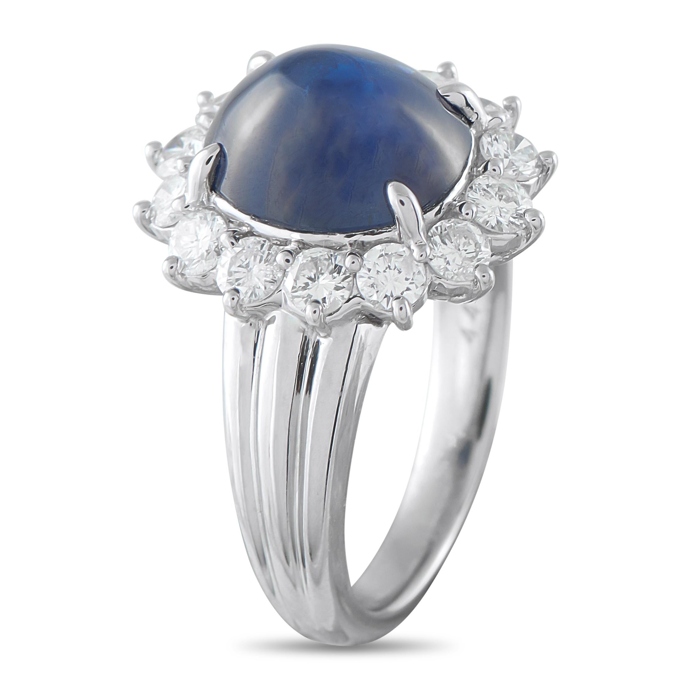 Making a sophisticated statement, this ring carries a substantial 4.43-carat sapphire cabochon at its core. The velvety blue gem with a smooth dome is held by four claw prongs and is framed by a sunburst halo of round diamonds. The design is