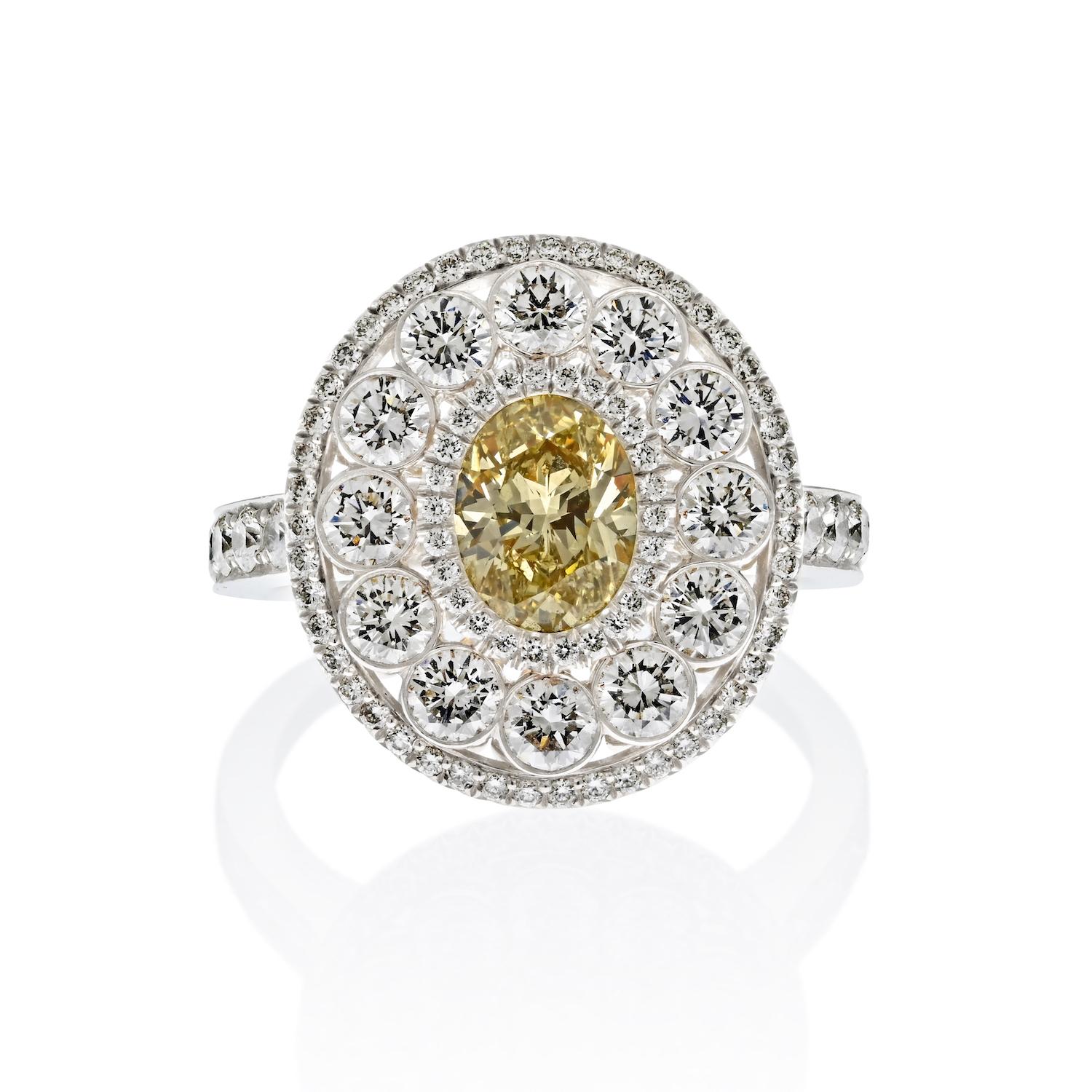This meticulously handmade ring is a fusion of elegance and artistry, crafted in a combination of platinum and 18k yellow gold.

At its heart, it boasts a radiant 1.03-carat light fancy yellow oval-cut diamond, graced with impeccable VS1