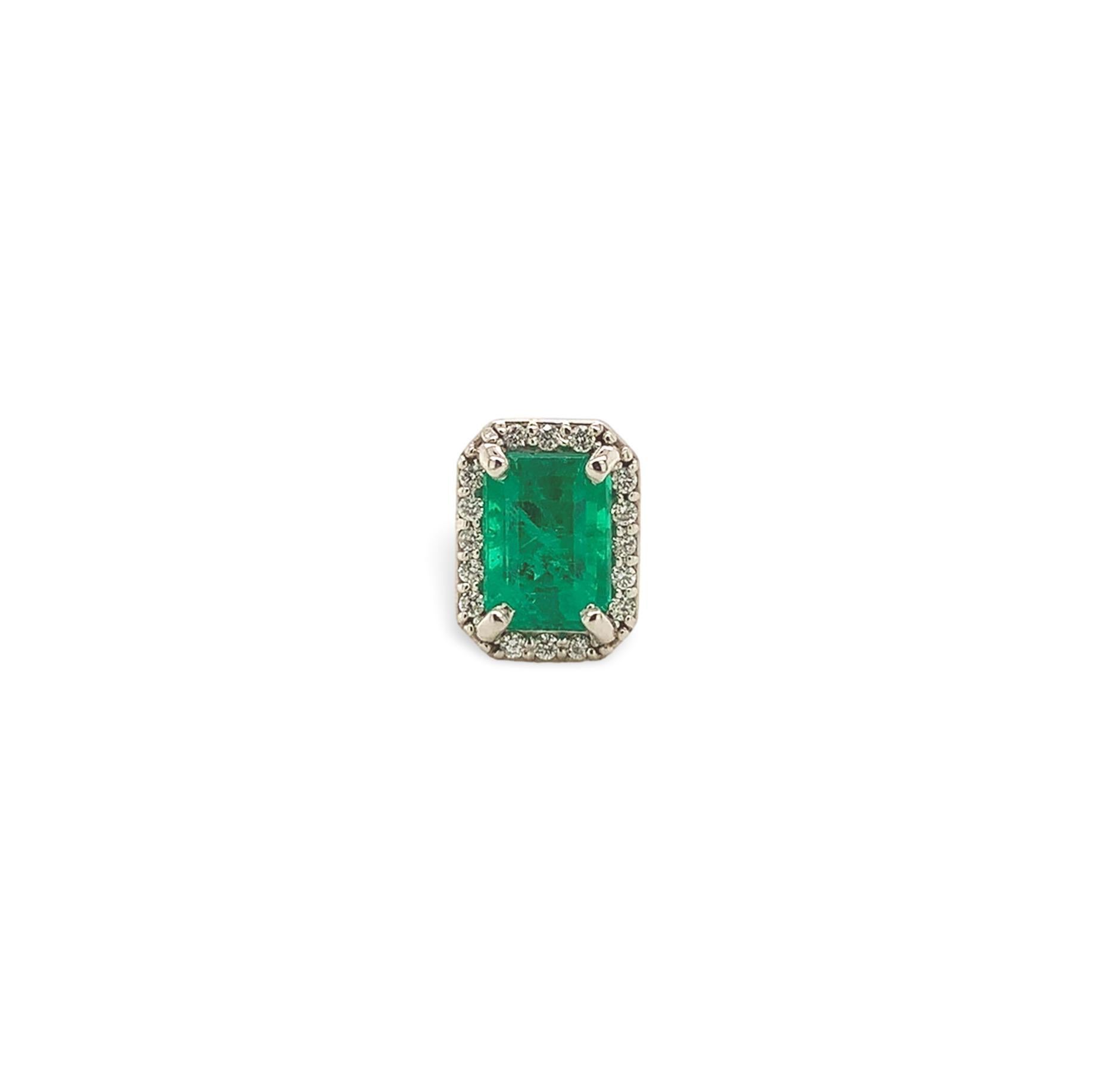 A pair of platinum genuine earth mined emerald stud earrings with diamond halos. The emerald cut emeralds measure about 5.7mm x 4mm and have medium dark color and fine clarity. The emeralds weigh 1.28 carats total. There are 32 tiny round diamond