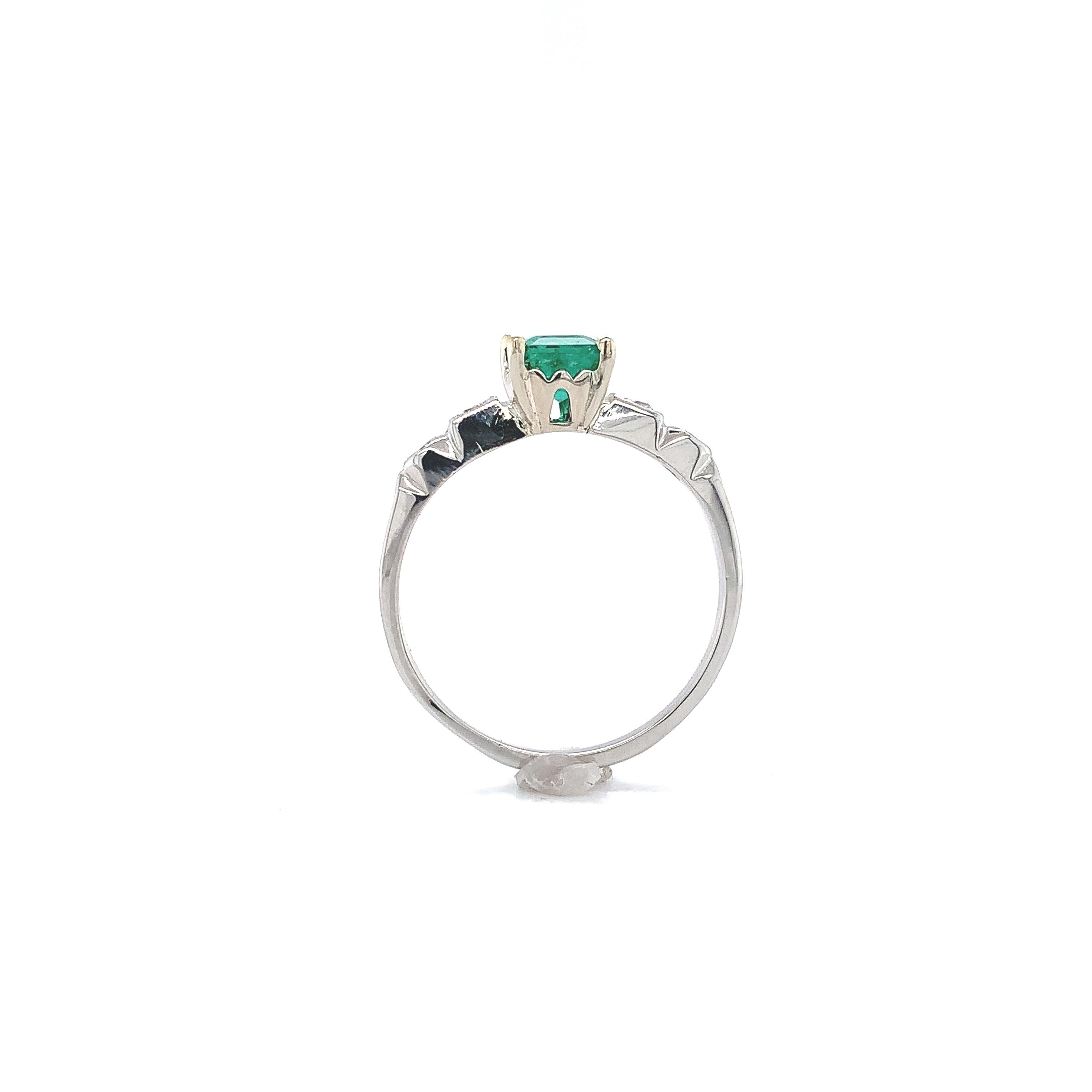 Platinum emerald and diamond ring featuring a genuine earth mined emerald weighing .82 carats with a 14K white gold head. The emerald is an emerald cut measuring 6mm x 5mm and has a bright grass green color. There are 4 small round diamond accents