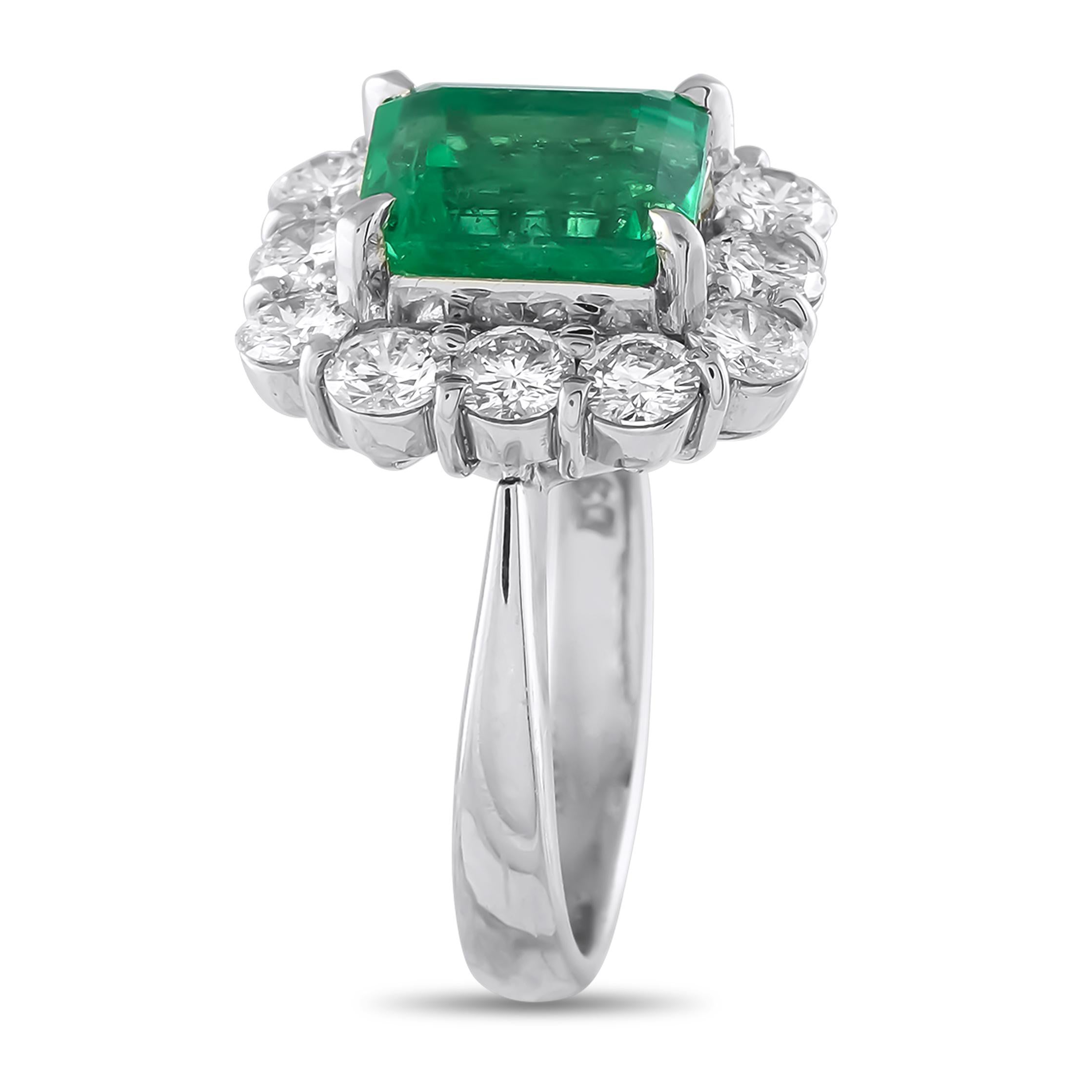 Rich color and radiant brilliance merge in this platinum ring. Of vintage charm, this piece is designed with a step-cut emerald on four claw prongs, haloed by diamonds on shared prongs. The dazzling contrast of vivid green and icy white sparkle