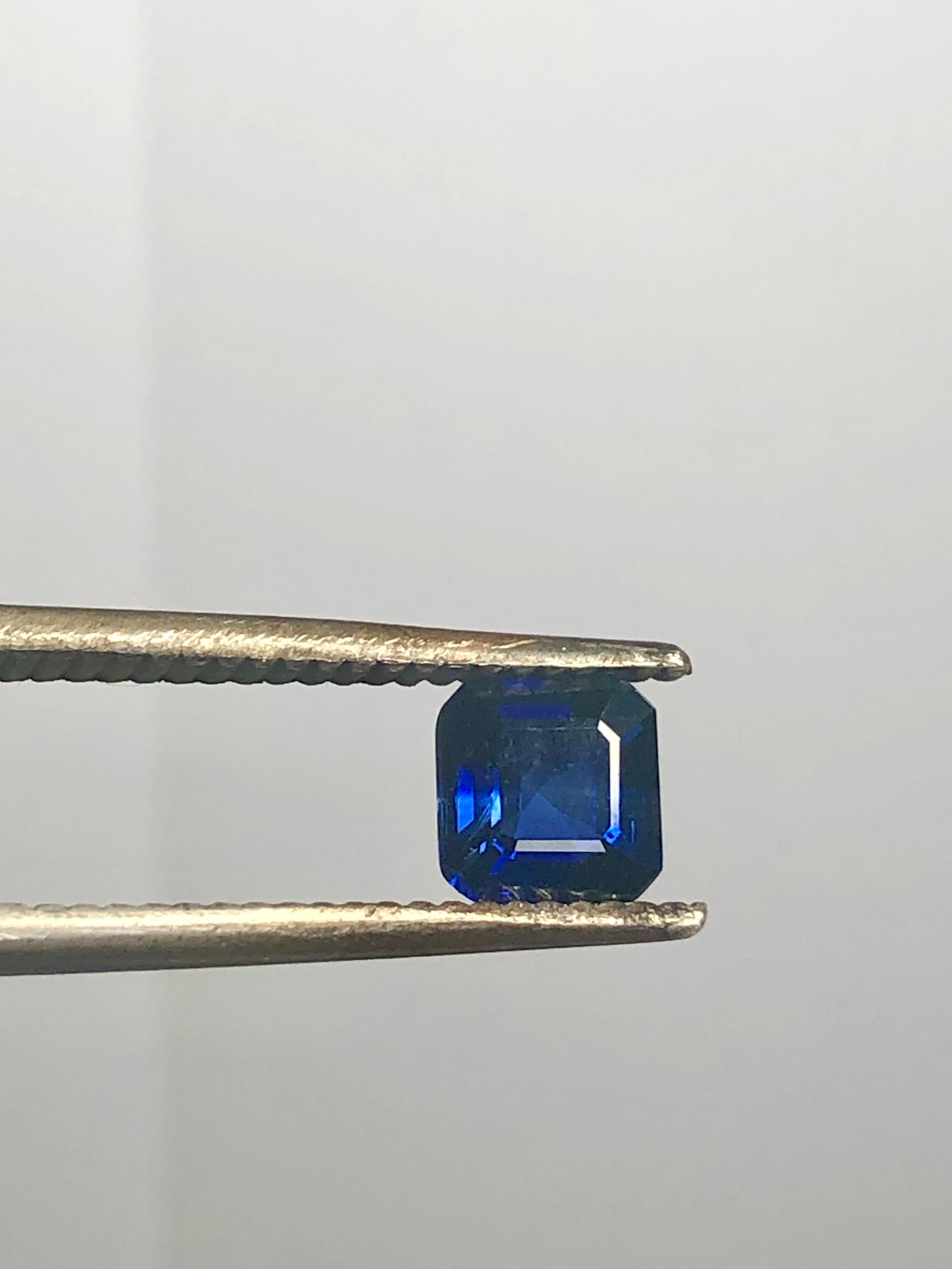 Un anello di fidanzamento senza tempo, che mette in mostra uno zaffiro blu fiordaliso a bassa temperatura riscaldato da 1,00 carati, incastonato in una classica montatura a quattro punte. Affiancato da due diamanti naturali taglio smeraldo con un