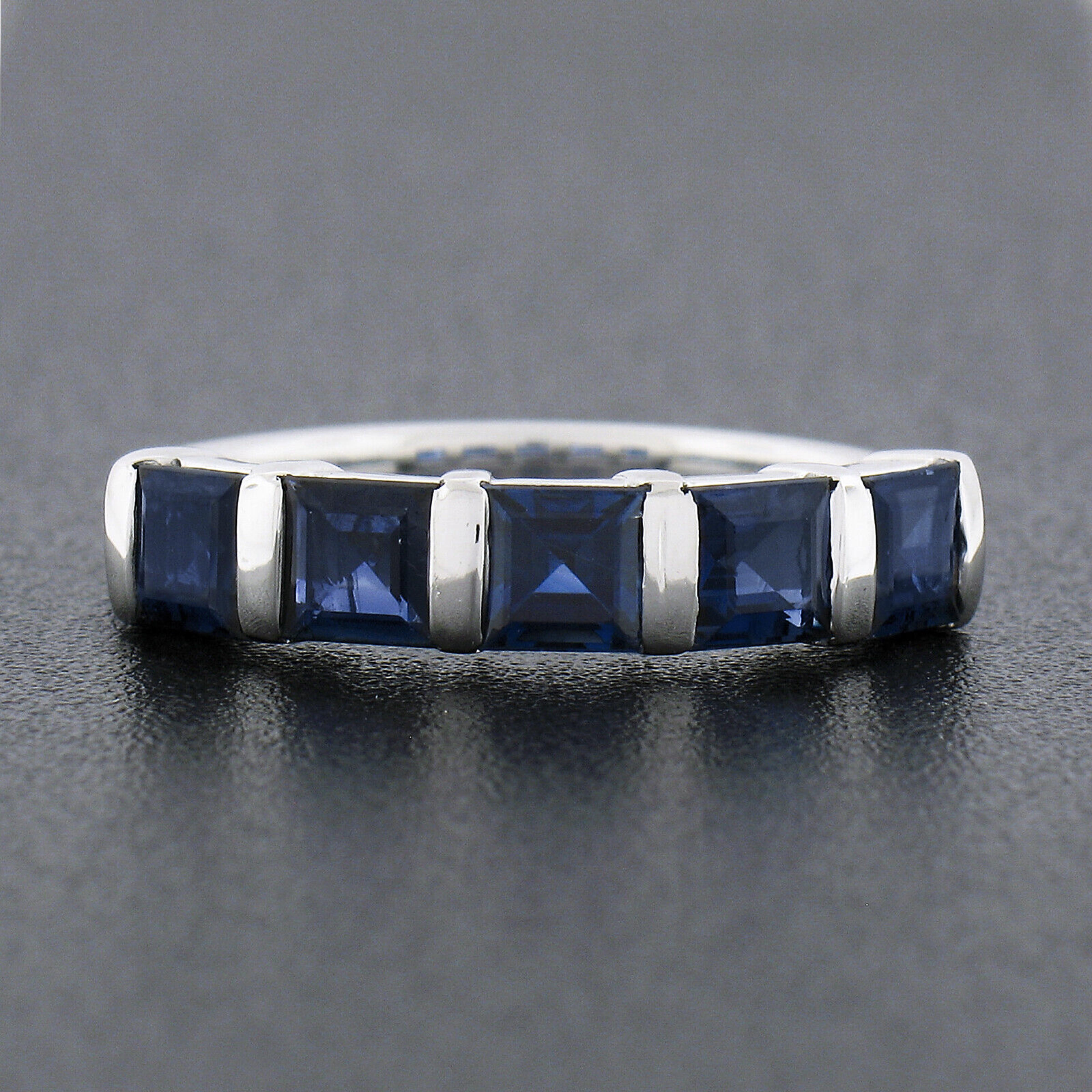 This magnificent and very well made band ring is crafted in solid platinum and features 5 genuine sapphire stones neatly bar channel set across the top. These fine sapphires are square step cut, totaling exactly 1.75 carats in weight, and are well