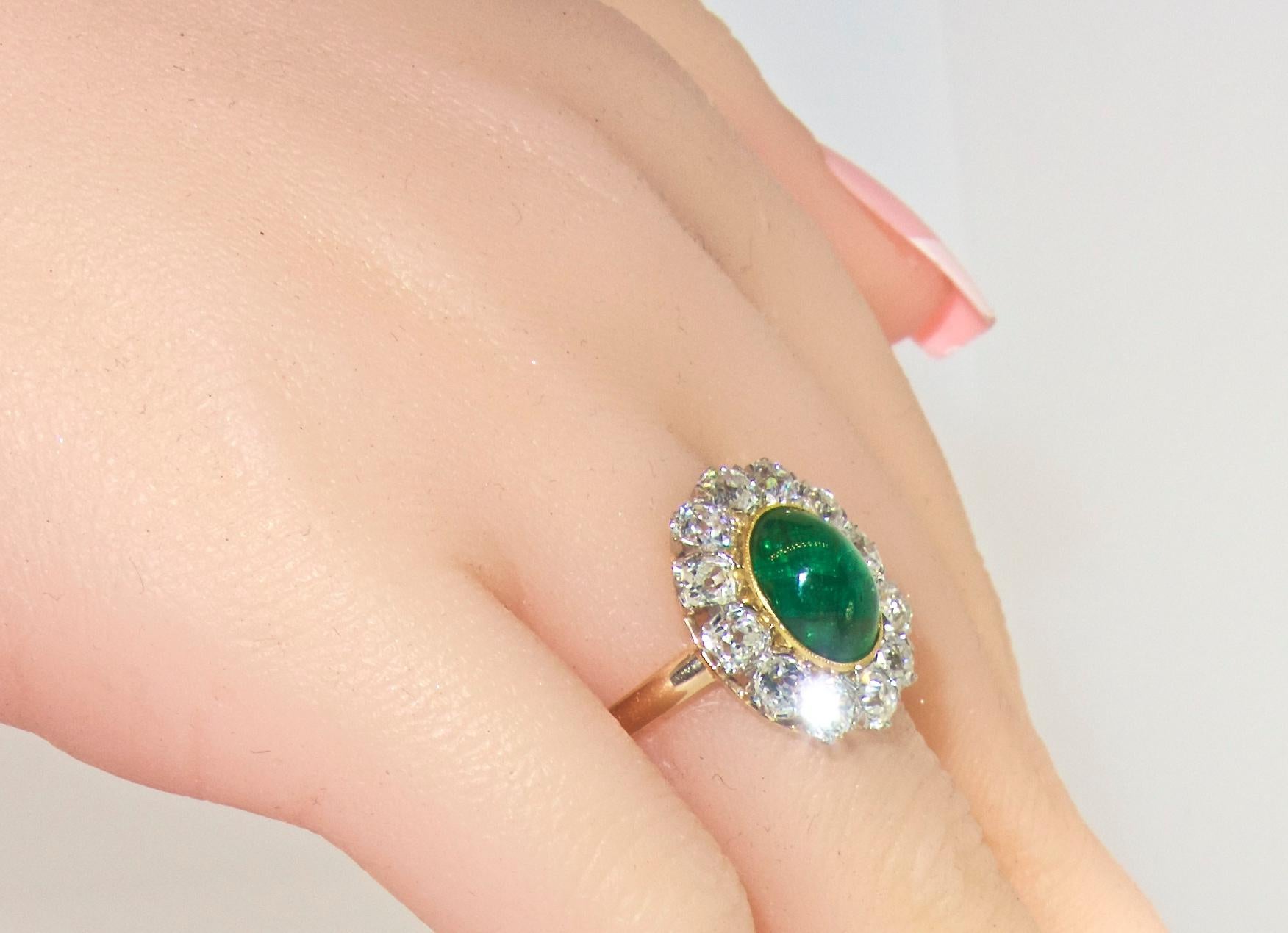 The center natural bright green emerald is a cabochon cut weighing approximately 3.5 cts.  This fine pure green emerald is surrounded by 12 old cut diamonds - all near colorless H/I and very slightly included (VS), weighing approximately 2.0 cts. 
