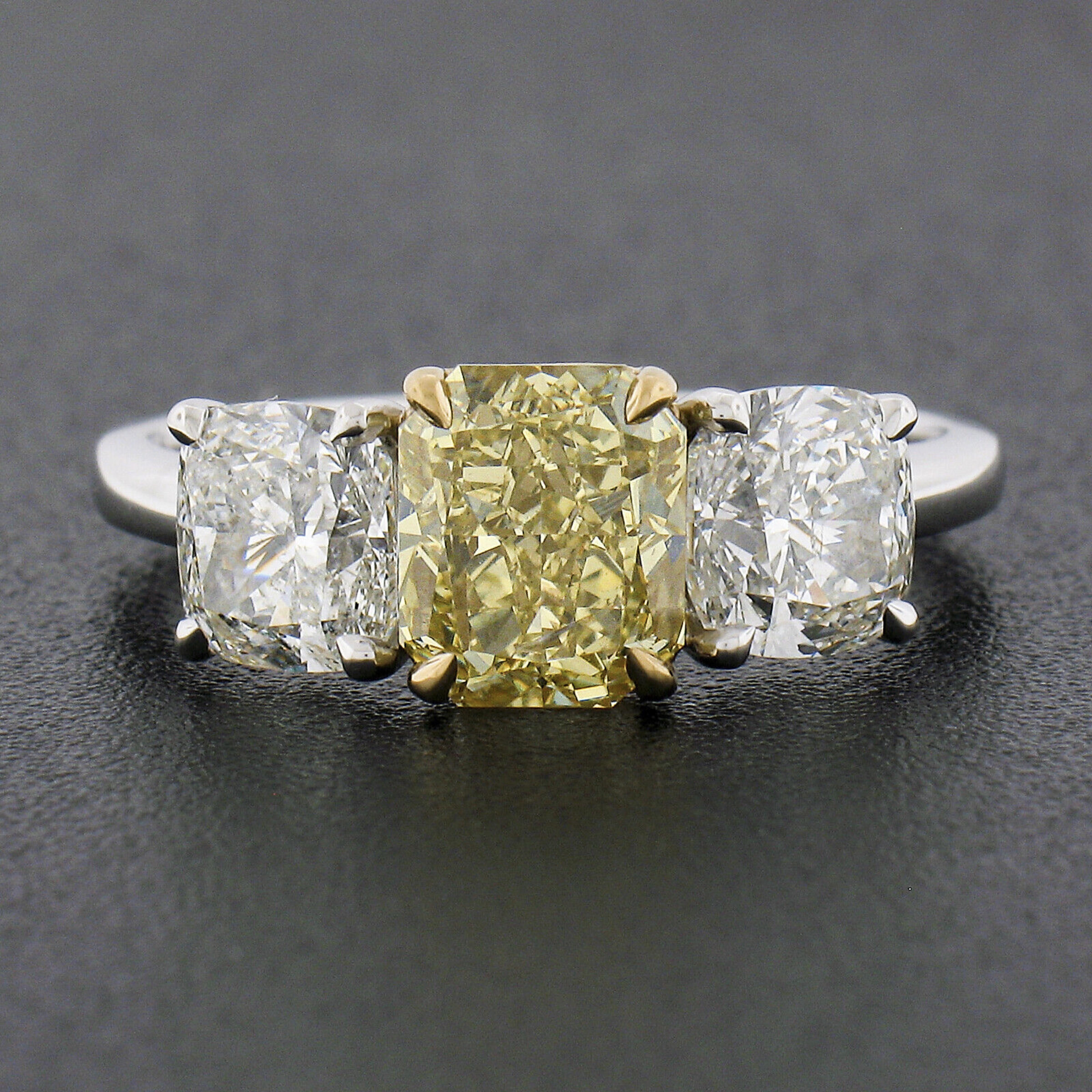 You are looking at a truly breathtaking engagement ring that is newly crafted from solid platinum with an 18k yellow gold center basket that carries a stunning, GIA certified, fancy yellow diamond. This gorgeous elongated radiant cut center diamond