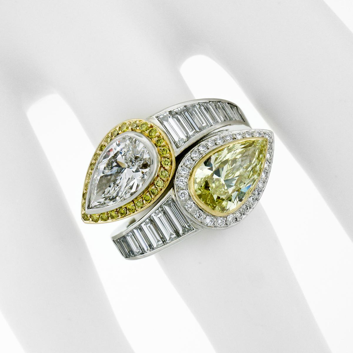 This absolutely magnificent bypass engagement/right hand ring was crafted from solid .950 platinum and 18k yellow gold and features a pair of large, GIA certified, pear cut diamonds - one fancy yellow and one colorless. The fancy yellow diamond