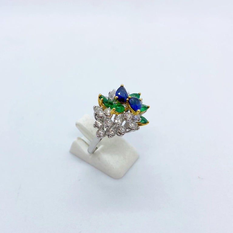 This beautiful Platinum set cocktail ring designed by Cellini Jewelers NYC, centers two pear shaped blue sapphires ( 1.13Ct. Total), surrounded by .89Ct. of pear shaped emeralds and 2.17Ct. of round brilliant diamonds. 
The Sapphires and Emeralds