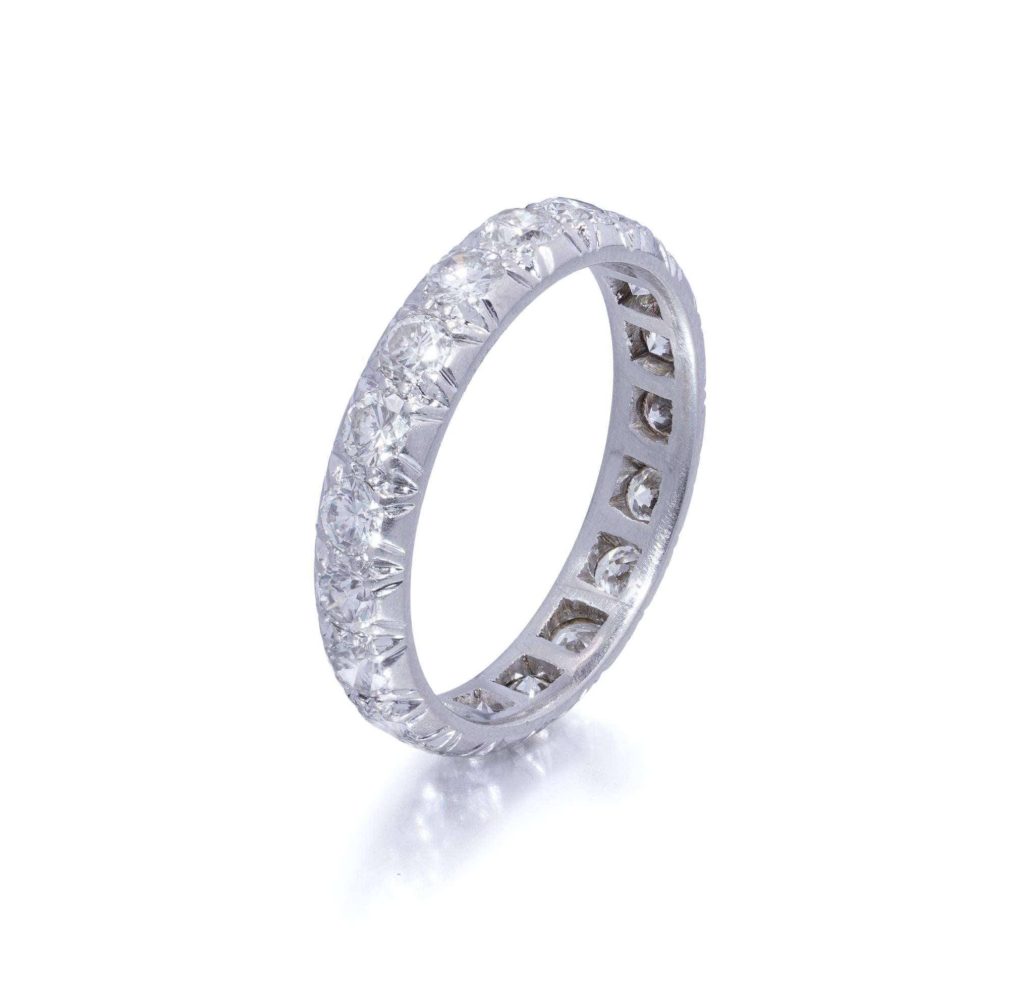 A classic platinum diamond eternity ring, pavé-set with 19 round brilliant-cut diamonds encircling the entire band. The diamonds are finely matched for colour and clarity, producing exceptional brilliance and fire across the full