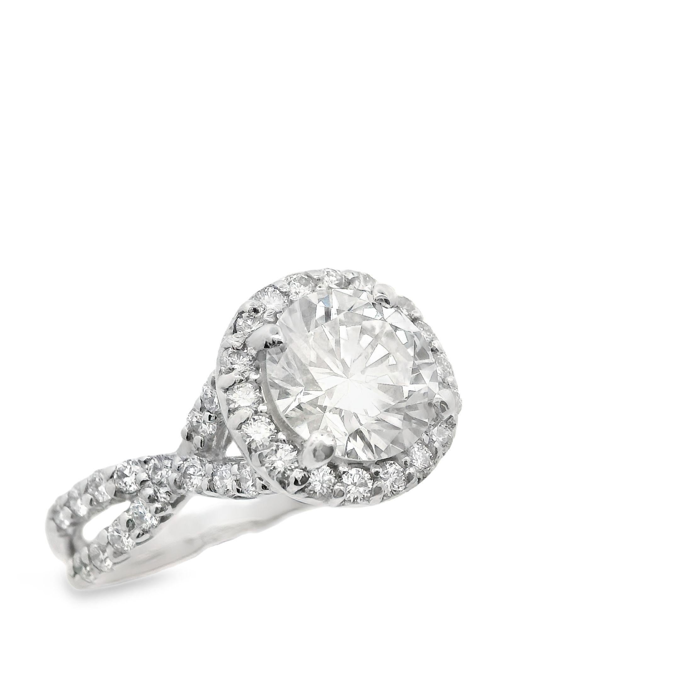 This platinum and 2+ carat diamond engagement ring is incredibly dynamic. This beautiful ring features a stunning 1.72 carat modern round brilliant center diamond that can be seen from across a room. Surrounding the center diamond is a halo of