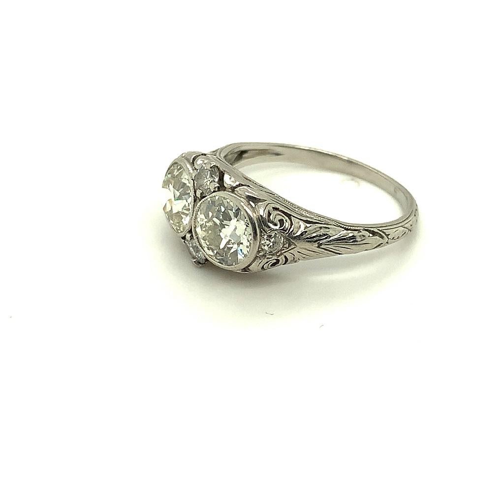 Ladies platinum antique diamond filigree ring containing two European cut diamonds weighing approximately 1 carat each. The setting is pieced and hand engraved. The diamonds are bezel set measuring approximately 6.5mm diameter and 3.5mm deep. The